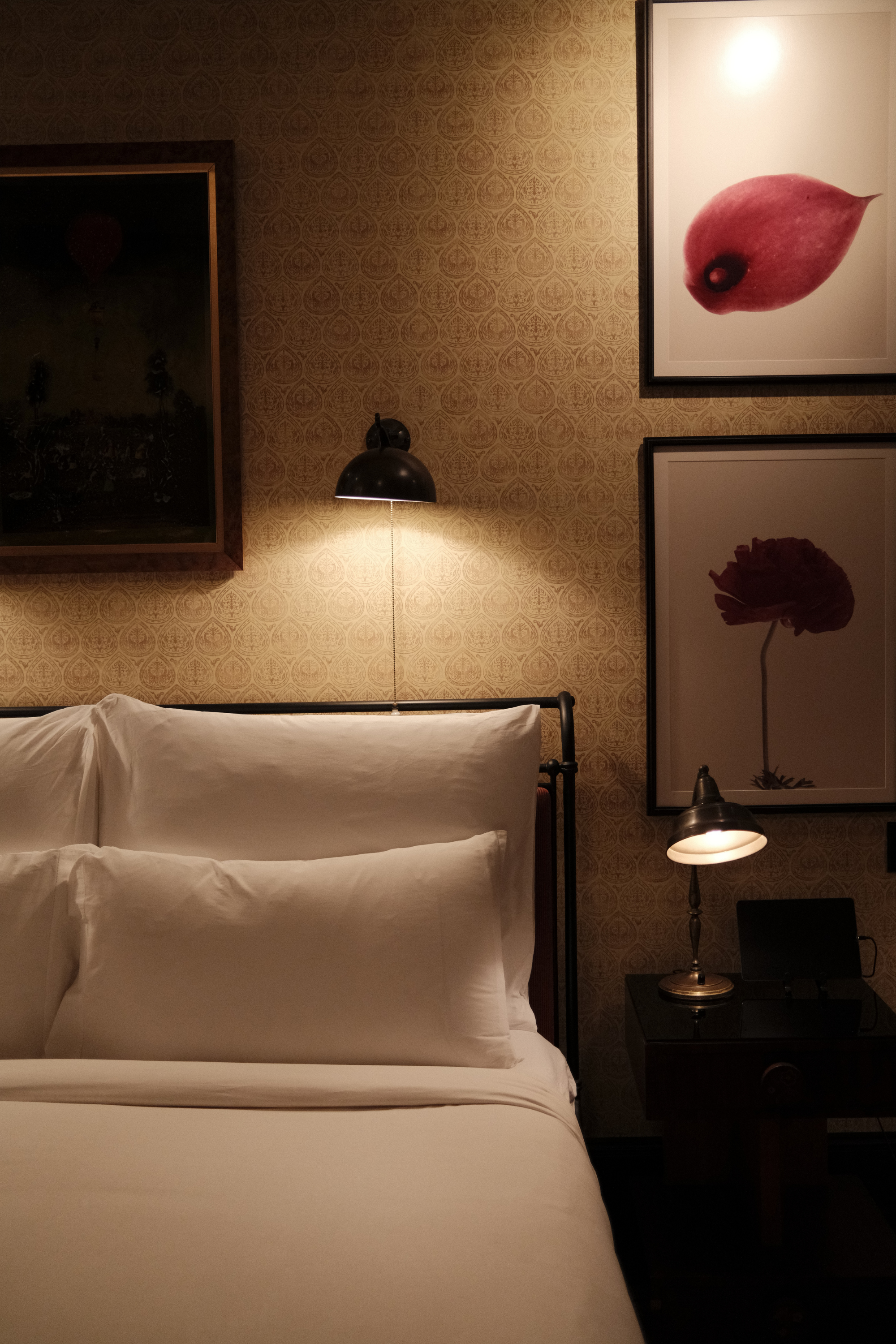 Side of bed and nightstand with art on wall