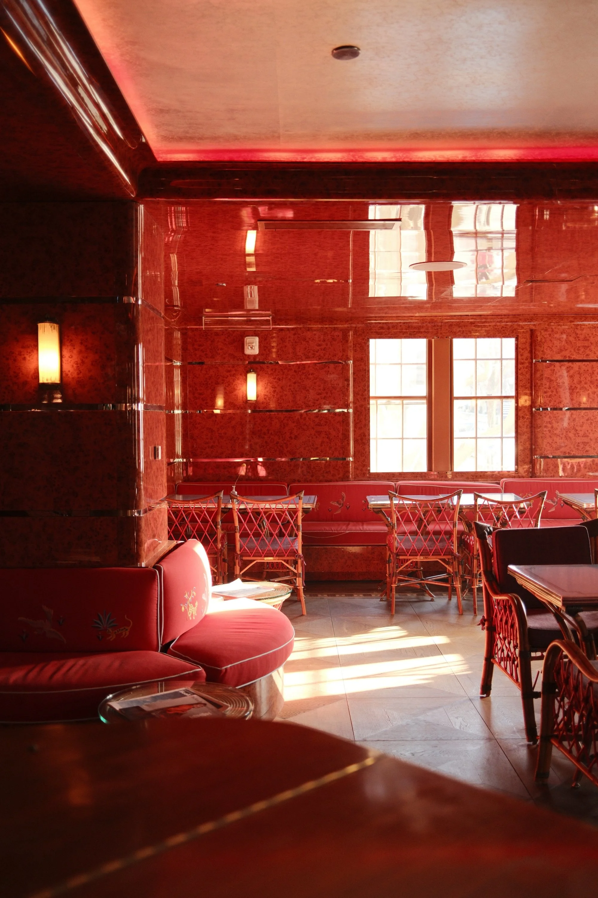 Restaurant interior with red decor, glossy burl wood walls, with wooden tables and chairs.