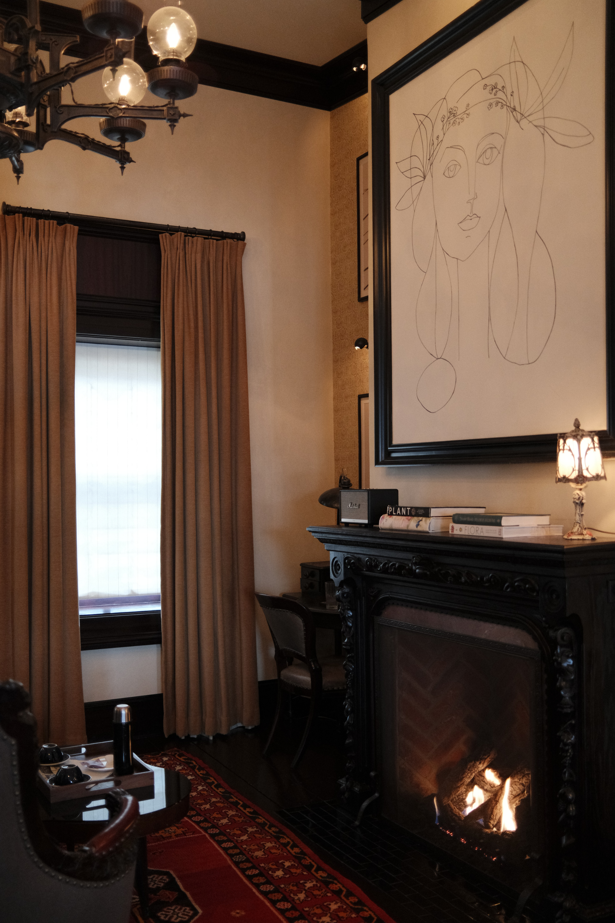 The Gardener fireplace with large artwork, writing desk, window, and seating area