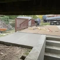Construction workers working on a project outside near a bridge, with tools and a truck visible in the background.