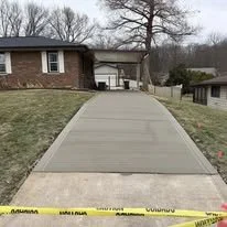 Concrete driveway leading up to a house, with a yellow caution tape at the bottom.