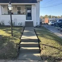 Concrete steps leading to the front door of a house with a sidewalk and grass on both sides.