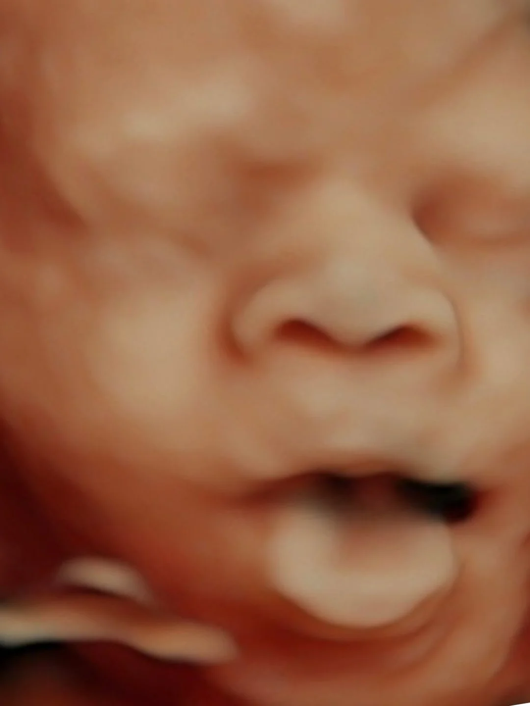 HD ultrasound image showing a close-up of baby's face with their tongue sticking out.