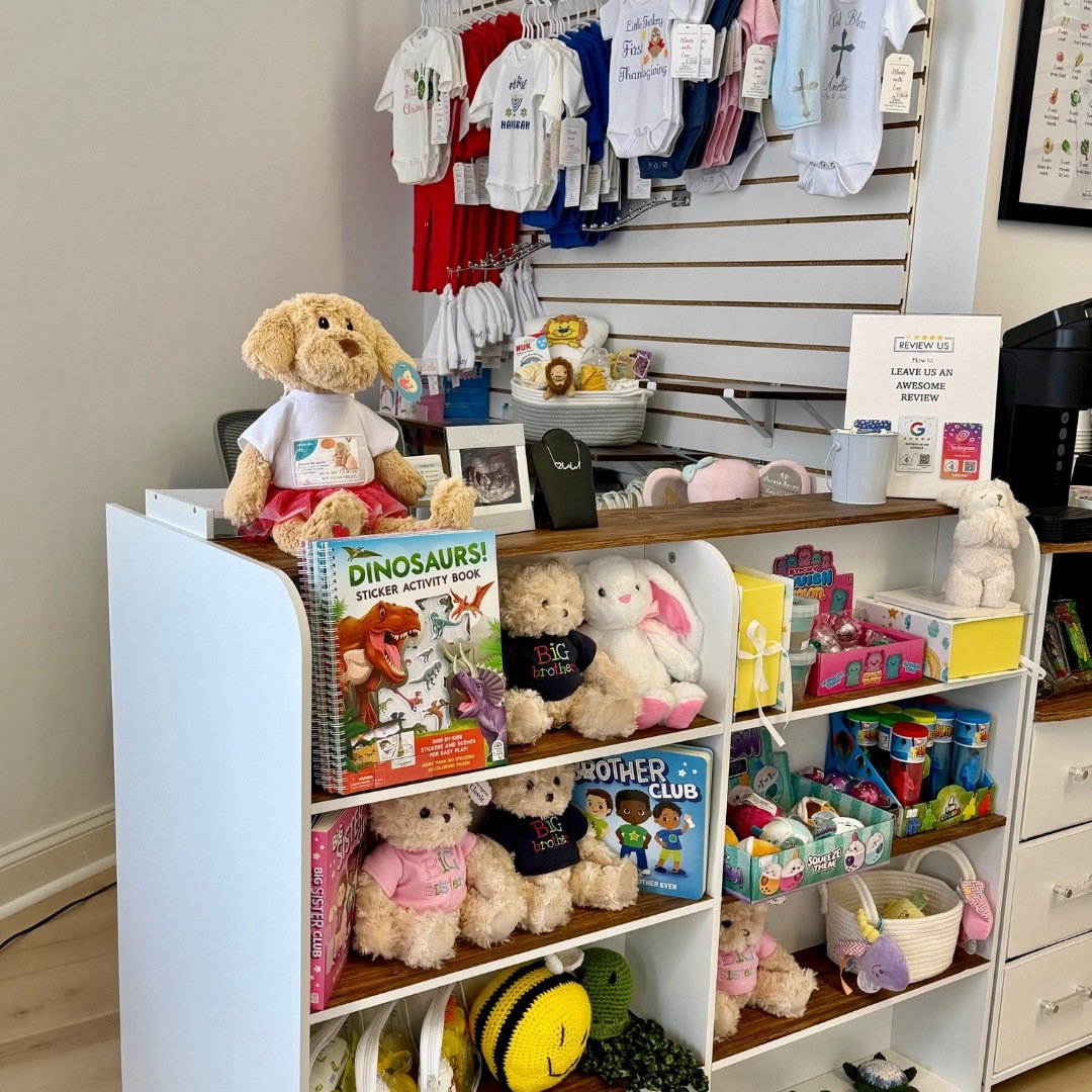 Boutique display featuring baby gifts, stuffed animals, books, and keepsake items.