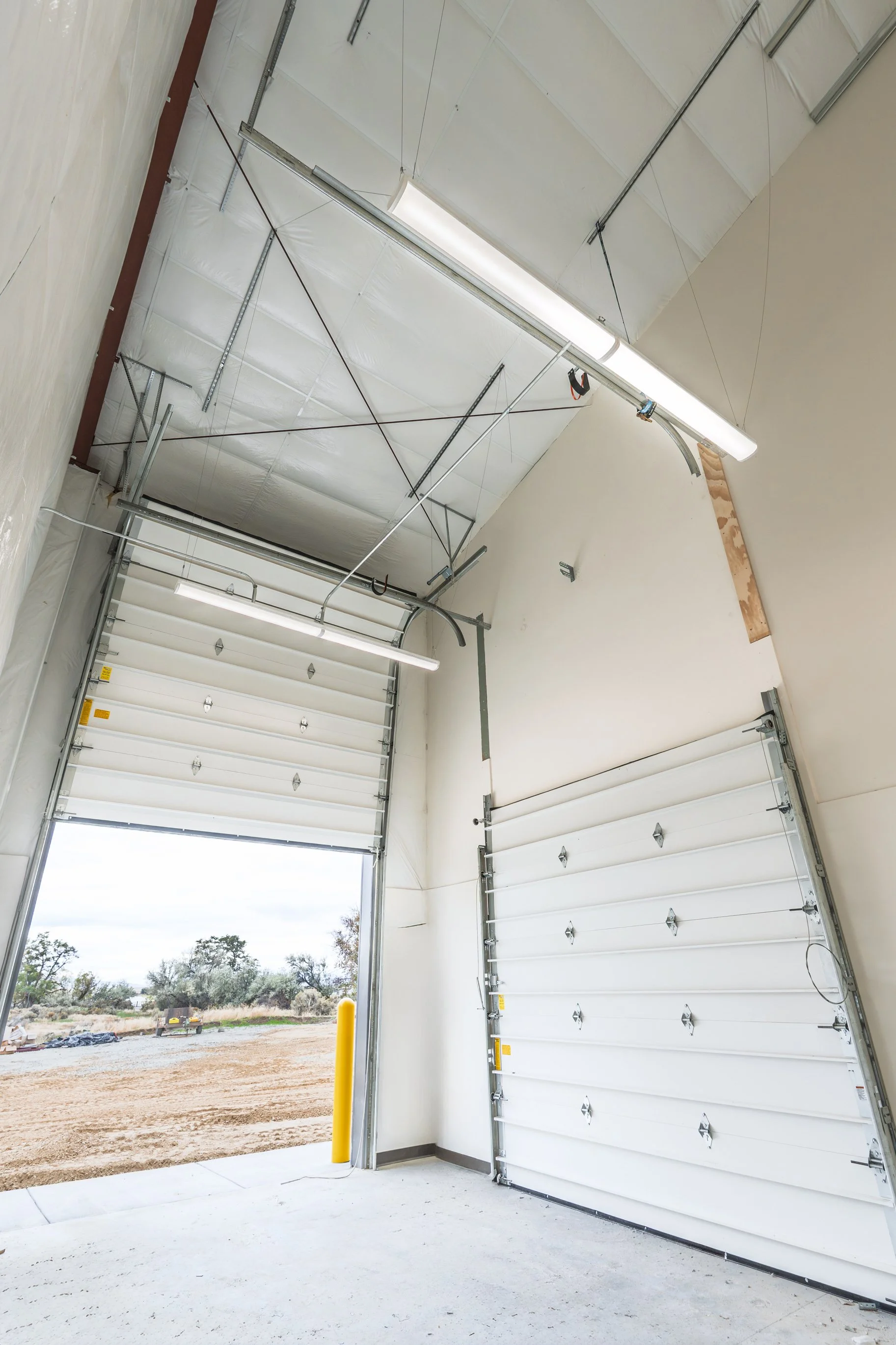 Open garage door leading to an outdoor area with trees and a cloudy sky.