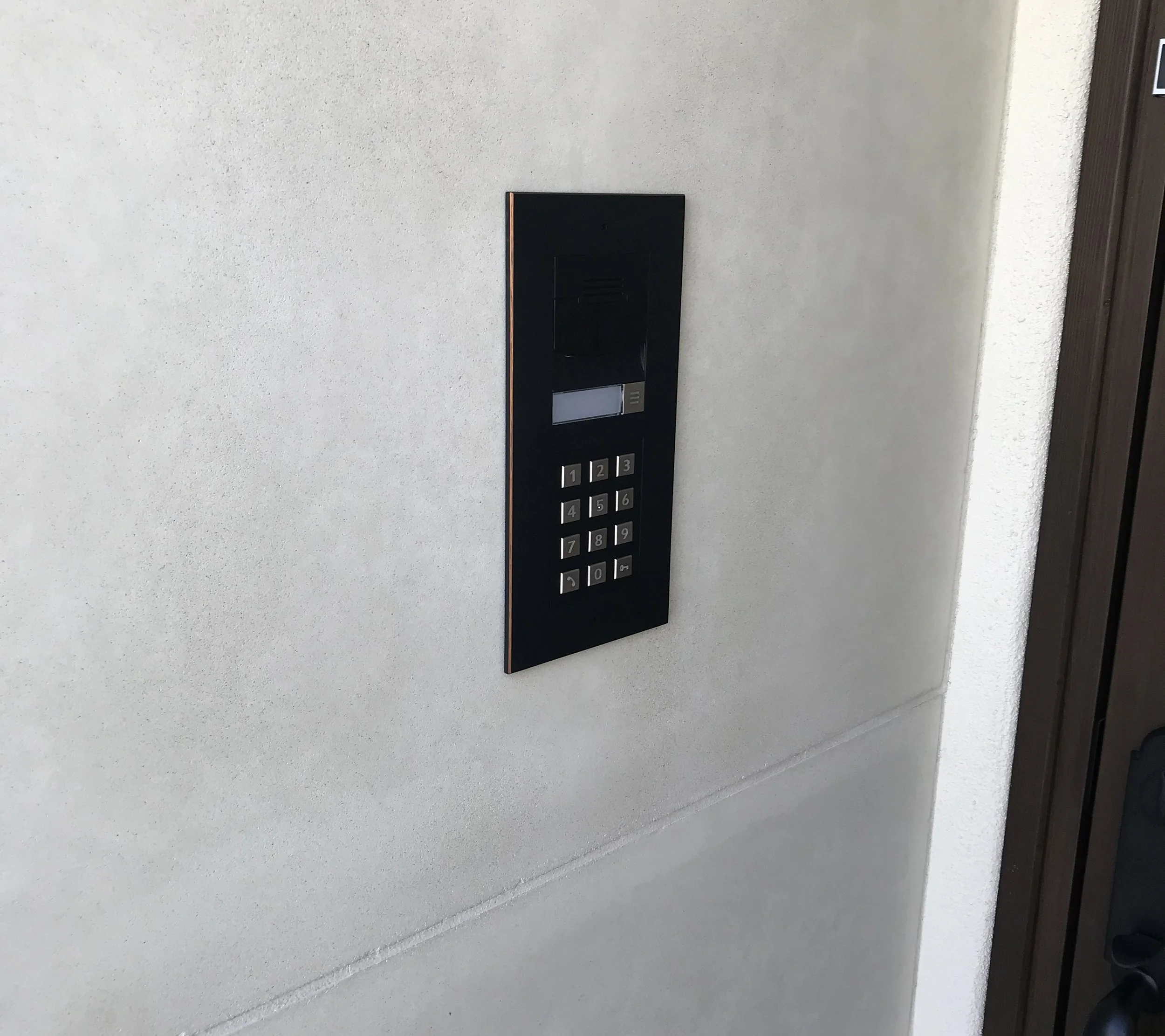 An elevator control panel with numbered buttons from 1 to 9 and an additional button for 0, mounted on a light-colored wall.