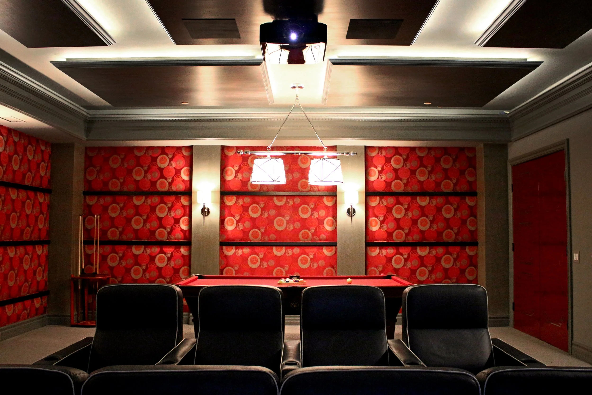 An interior room with a pool table, black chairs, floral red wallpaper, and ceiling lights.