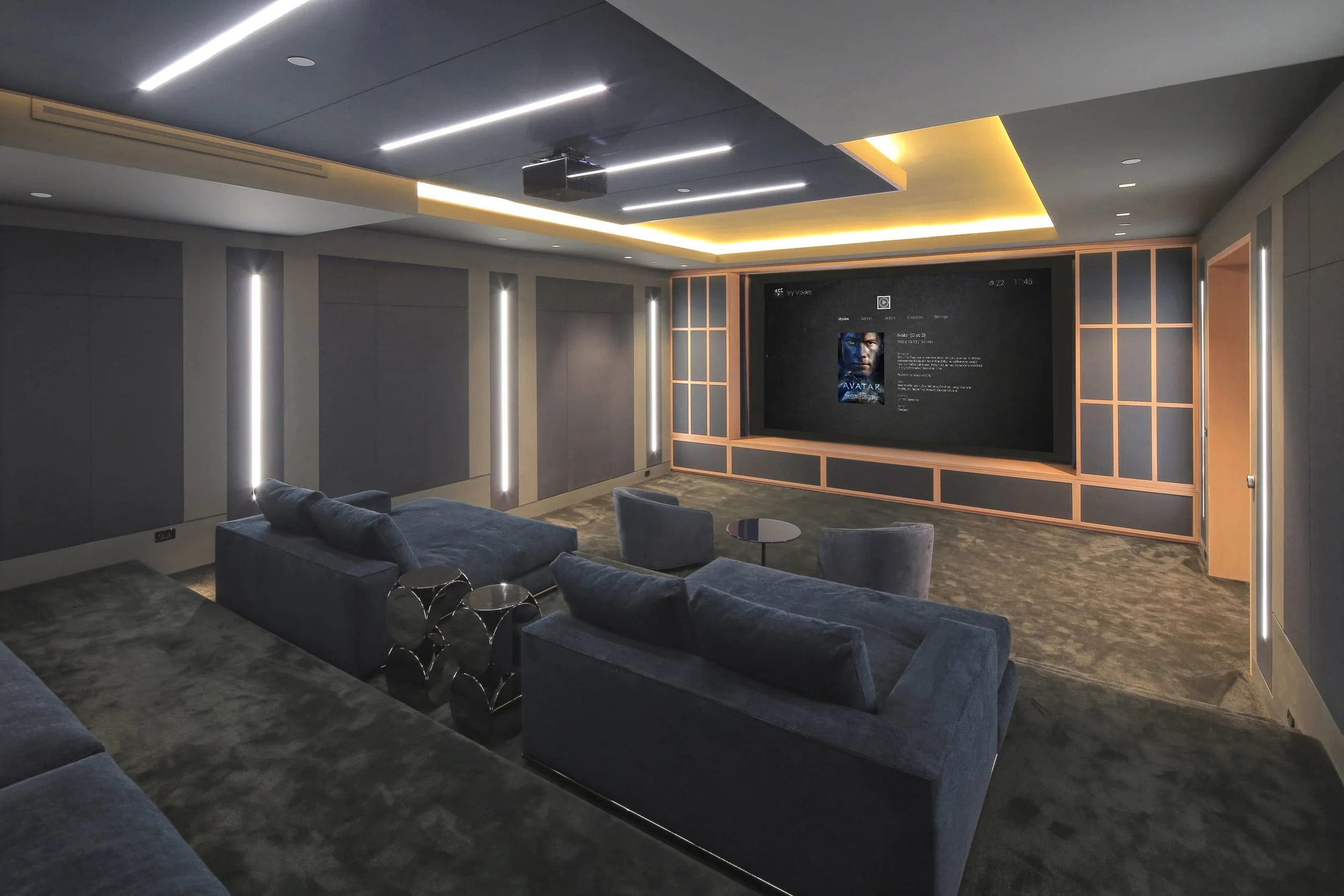 Modern home theater room with seating, large screen displaying movie information, and ambient lighting.