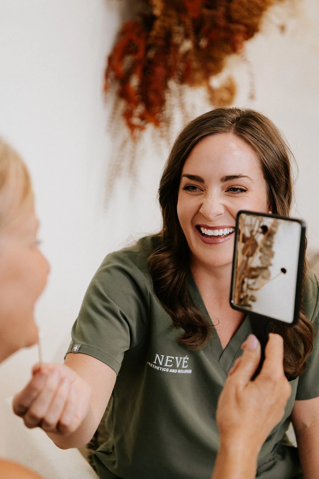 A Nevé provider with wavy brown hair, wearing green scrubs and interacting with a patient during a consultation