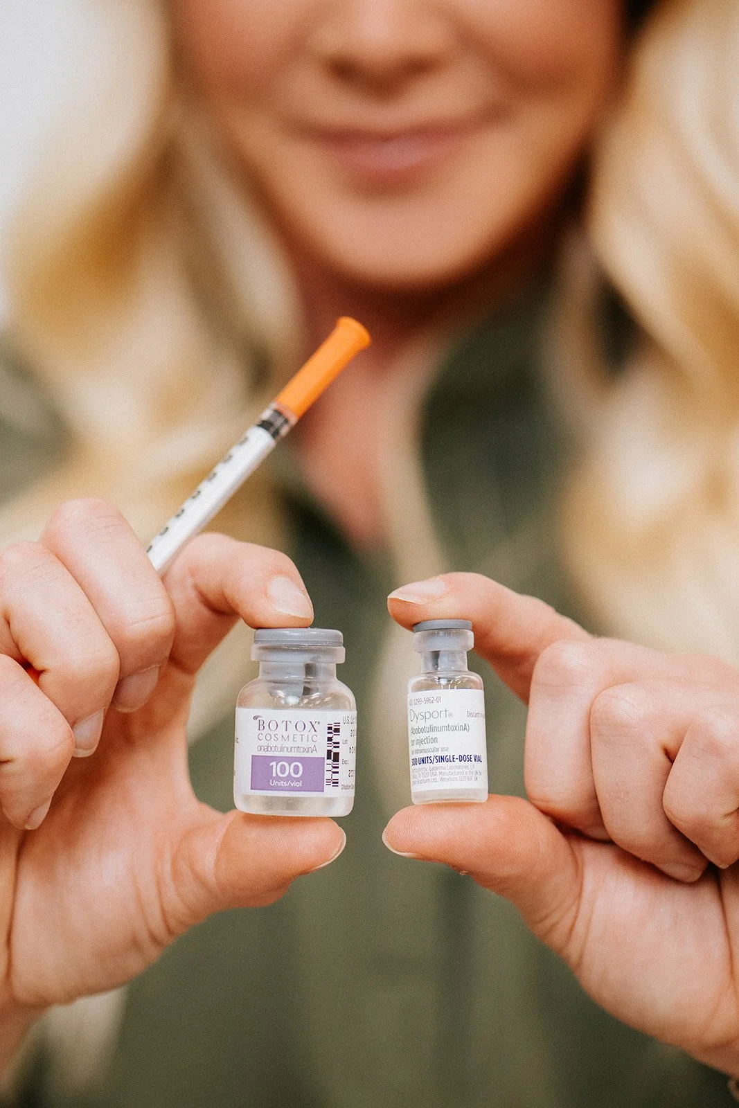 A woman holding vials of anti-wrinkle medication with a blurred background.