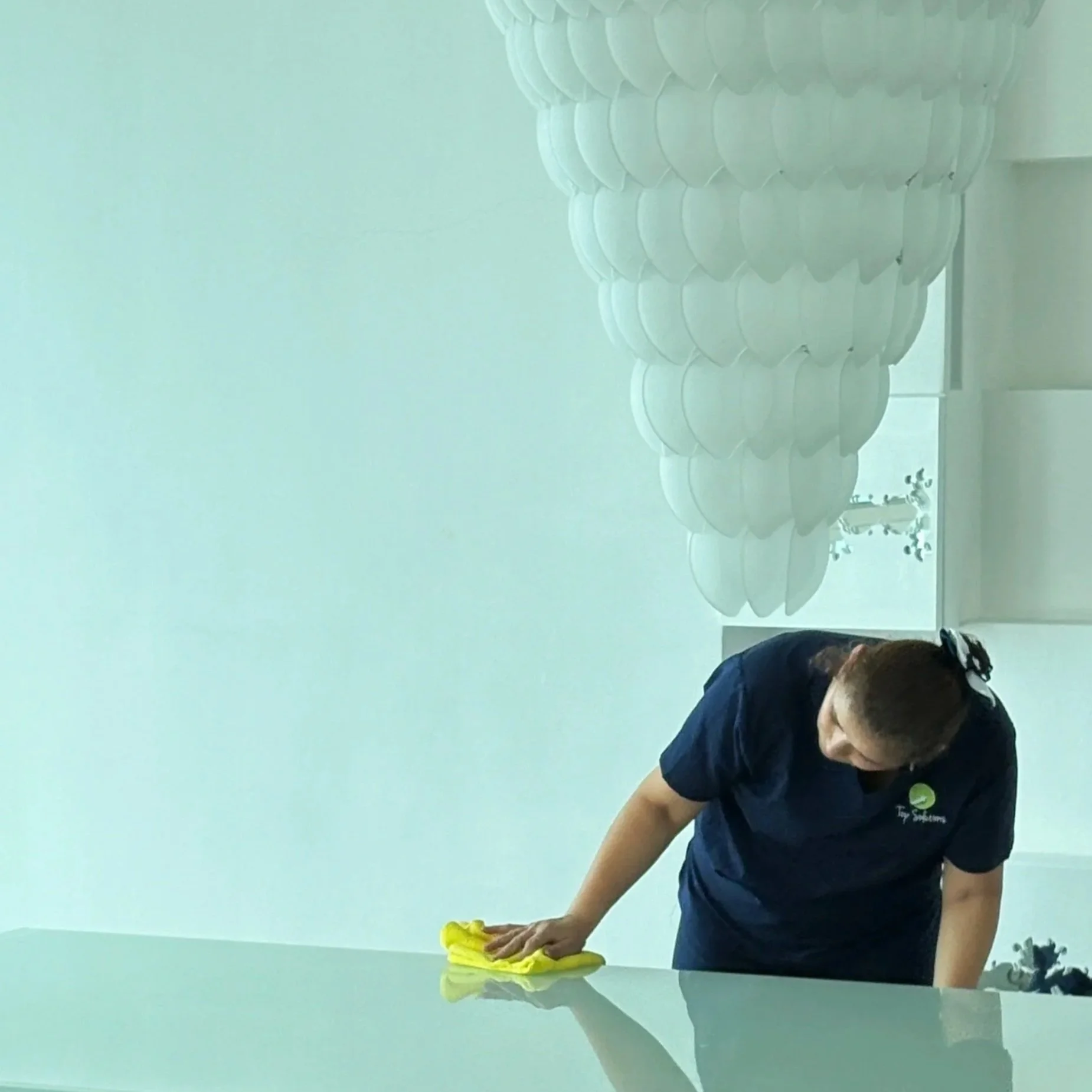 Persona limpiando una mesa con un paño amarillo en una sala de clases