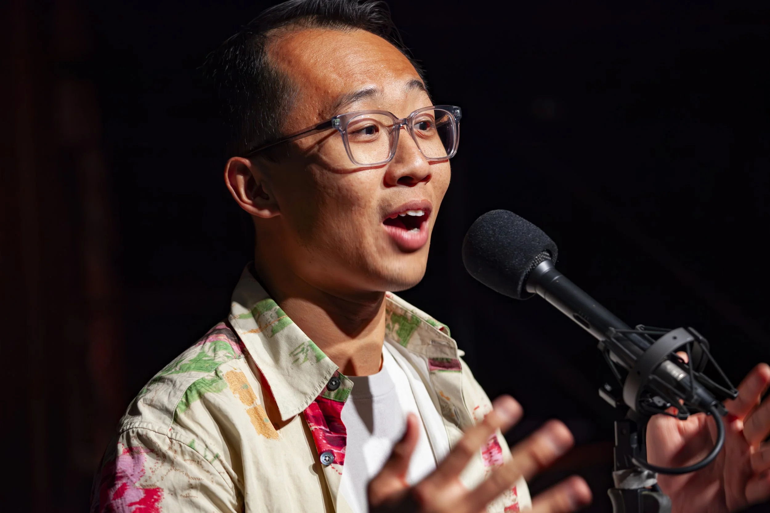 A photo of the author, Roger Lam: a young Chinese American telling a story into a microphone.
