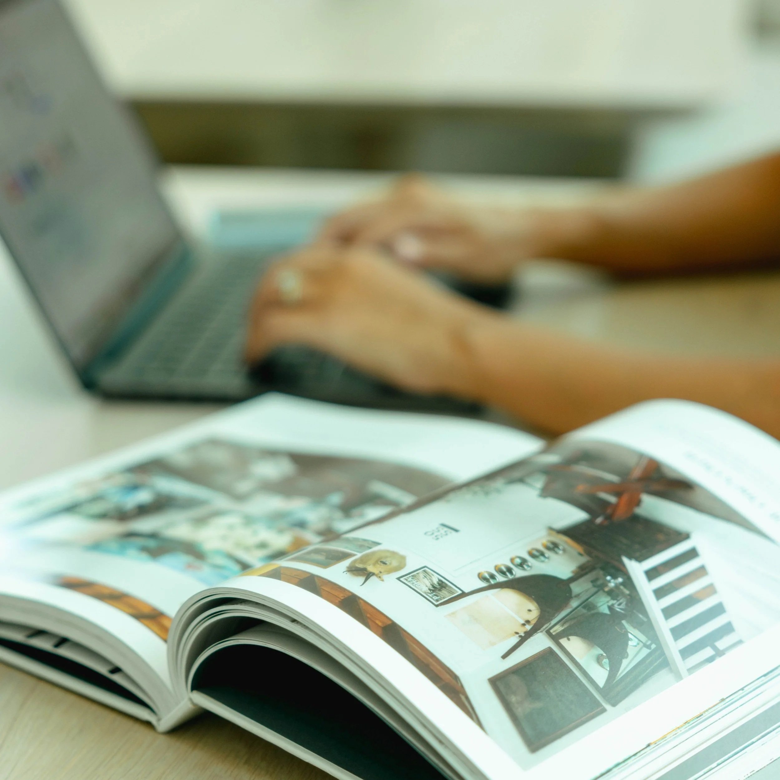 Open magazine or catalog with colorful images of furniture and interior designs, laid out on a table.