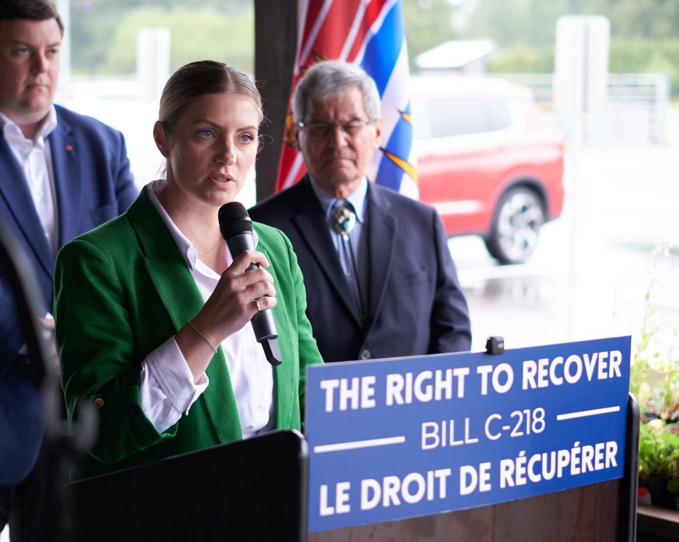 Alicia Duncan speaking at a podium during a press conference about Medical Assistance in Dying (MAiD).