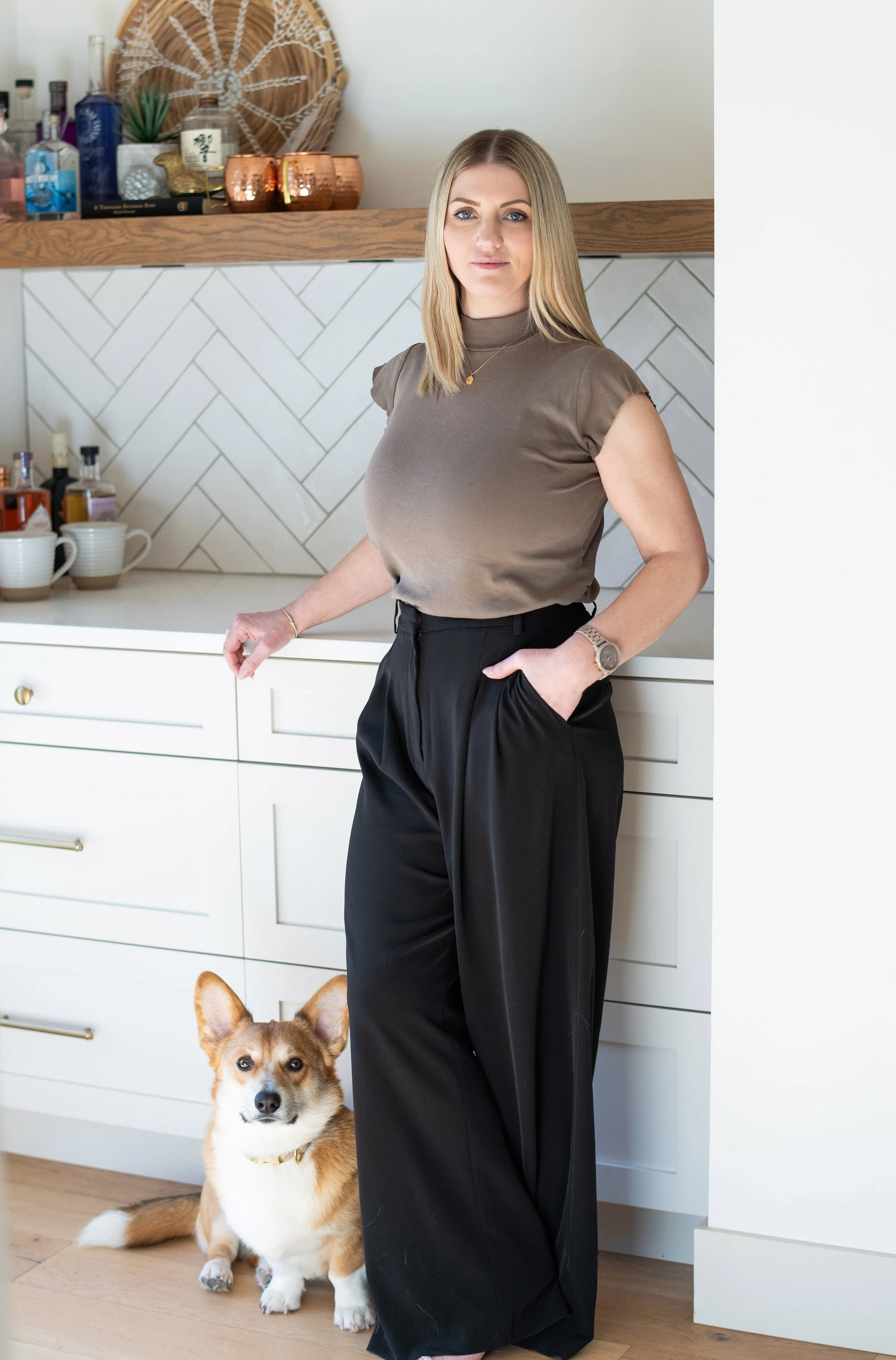 Alicia Duncan, author of The Other Side of the Straitjacket, speaker, and advocate for transparency and accountability in Canada's MAiD system. She is standing in her kitchen beside her Corgi.