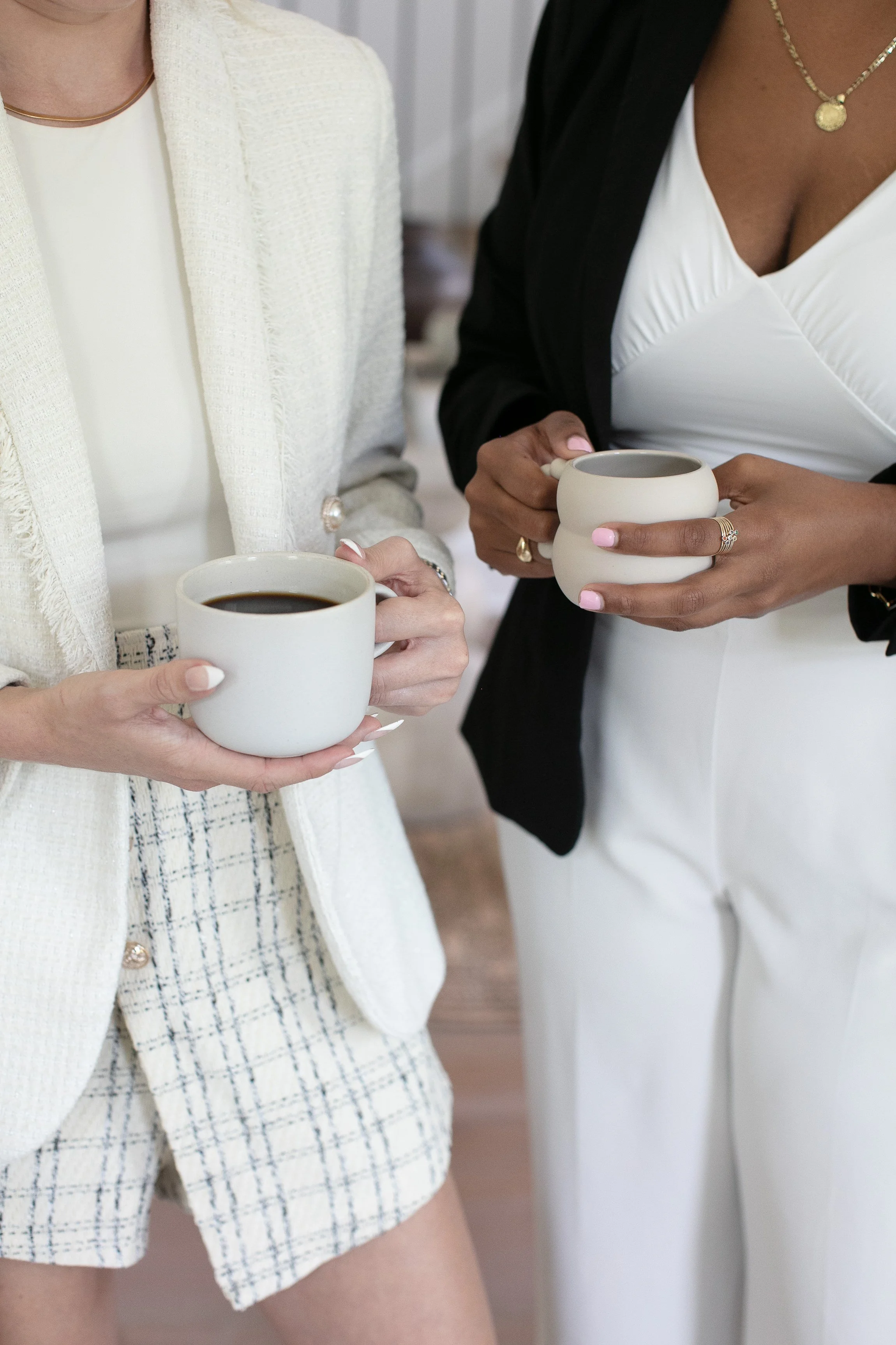 Two women holding mugs of coffee in a professional setting