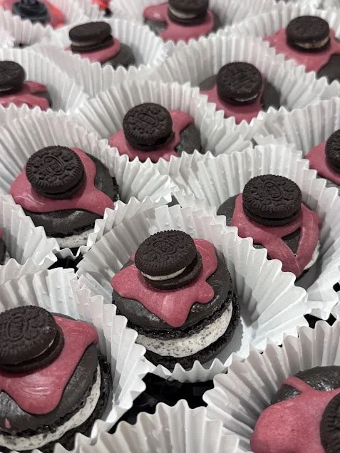 Black cocoa macarons with Oreo filling, topped with red, chocolate ganache and a mini-Oreo.