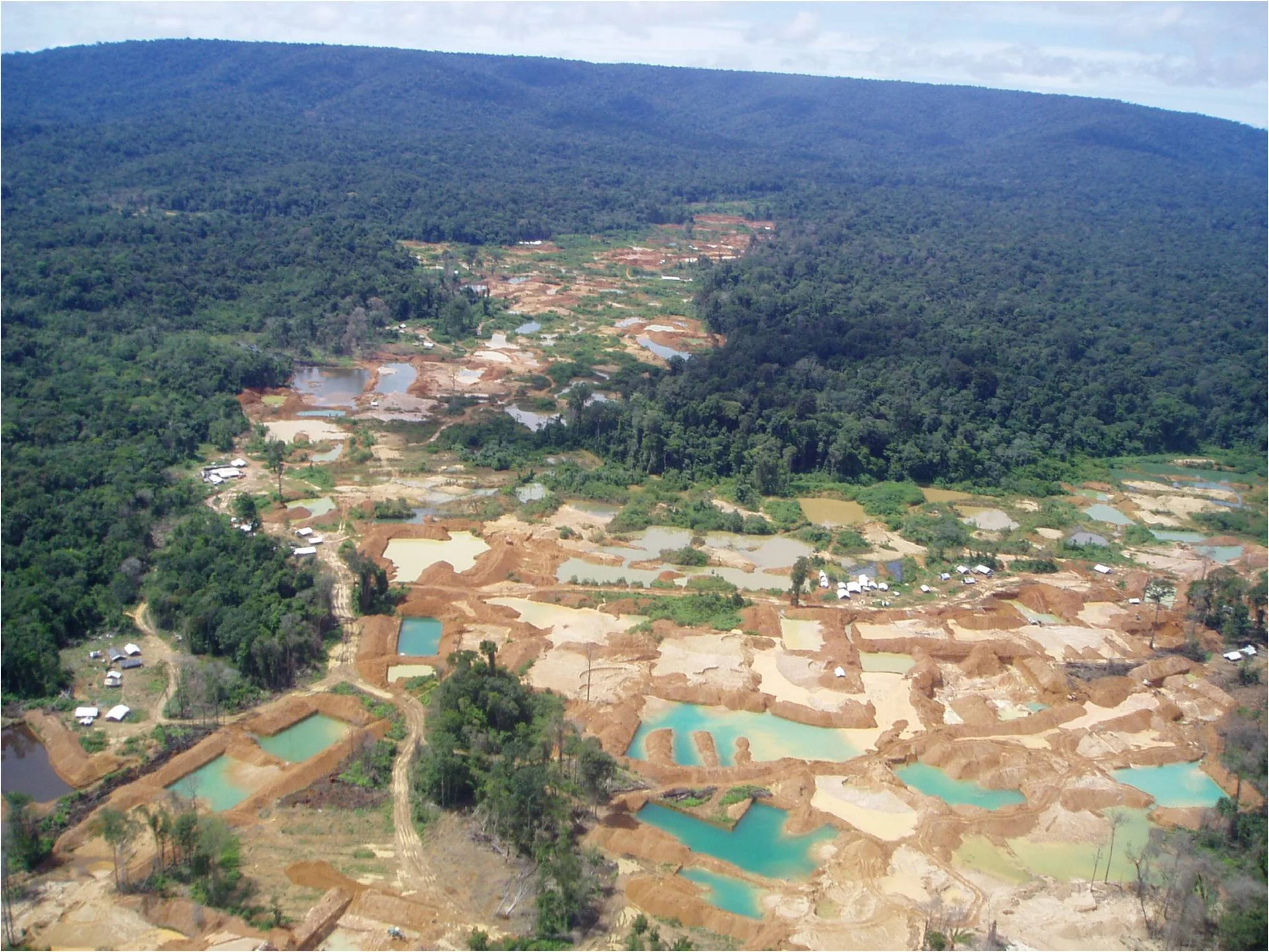 Artisanal and small-scale gold mine (ASGM) workings form a mosaic of small blue-coloured pools. These ASGM workings can be primary (veins are directly below the surface) or secondary (gold is alluvial).