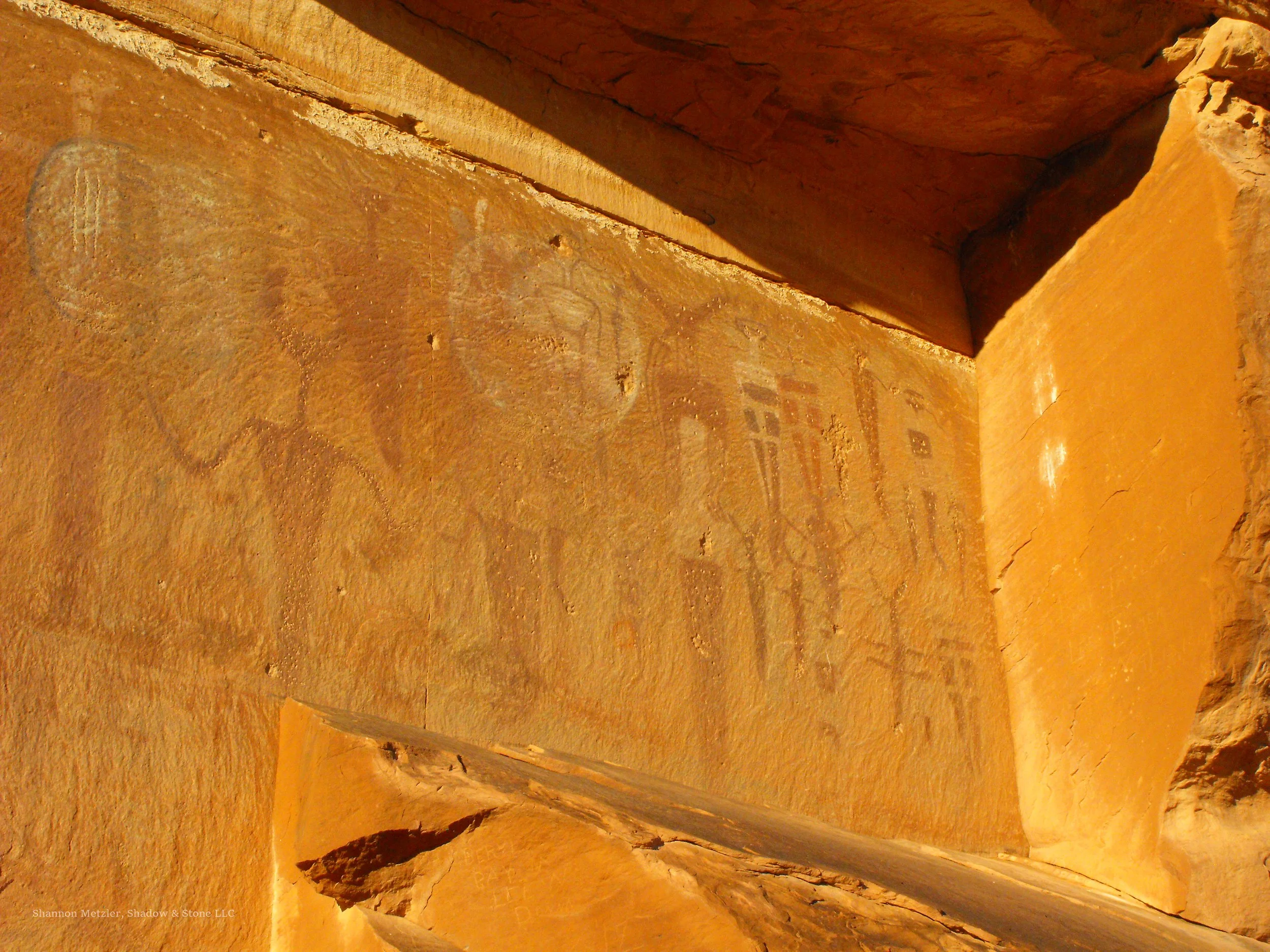 View of ancient pictograph painted on a reddish-brown stone walls of a rock shelter. The phot shows the aftermath of vandalism that drastically altered the various painted geometric patterns and symbols.