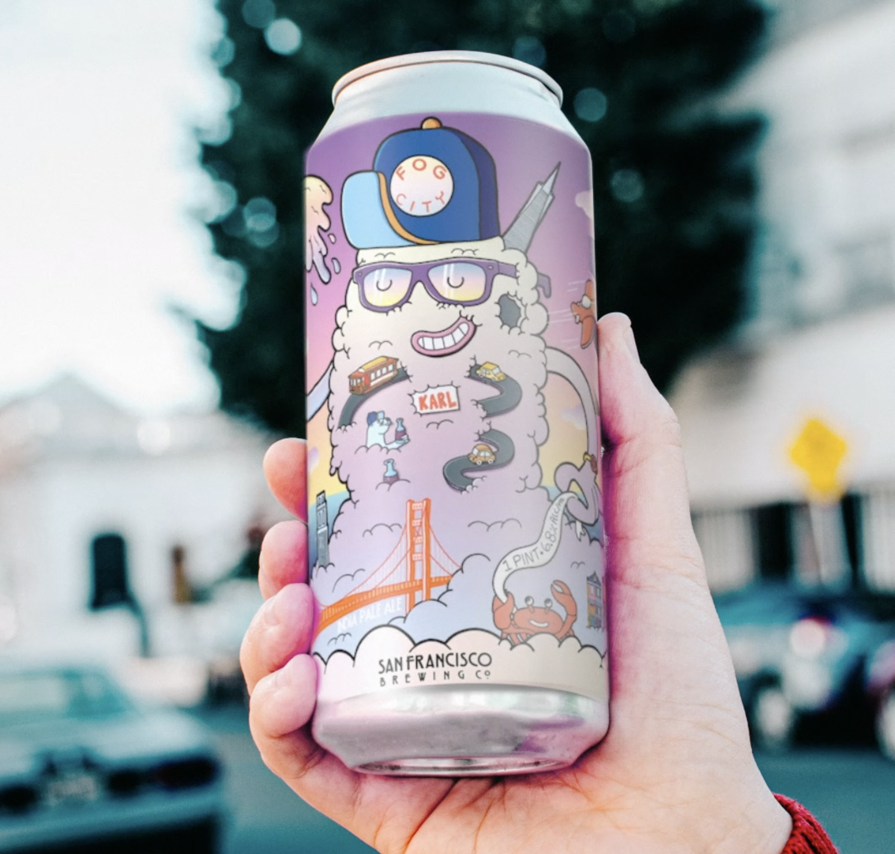 Hand holding San Francisco Brewing Co. Fog City Hazy IPA can — Danvillage beer can label illustration showing Karl the Fog character and SF landmarks