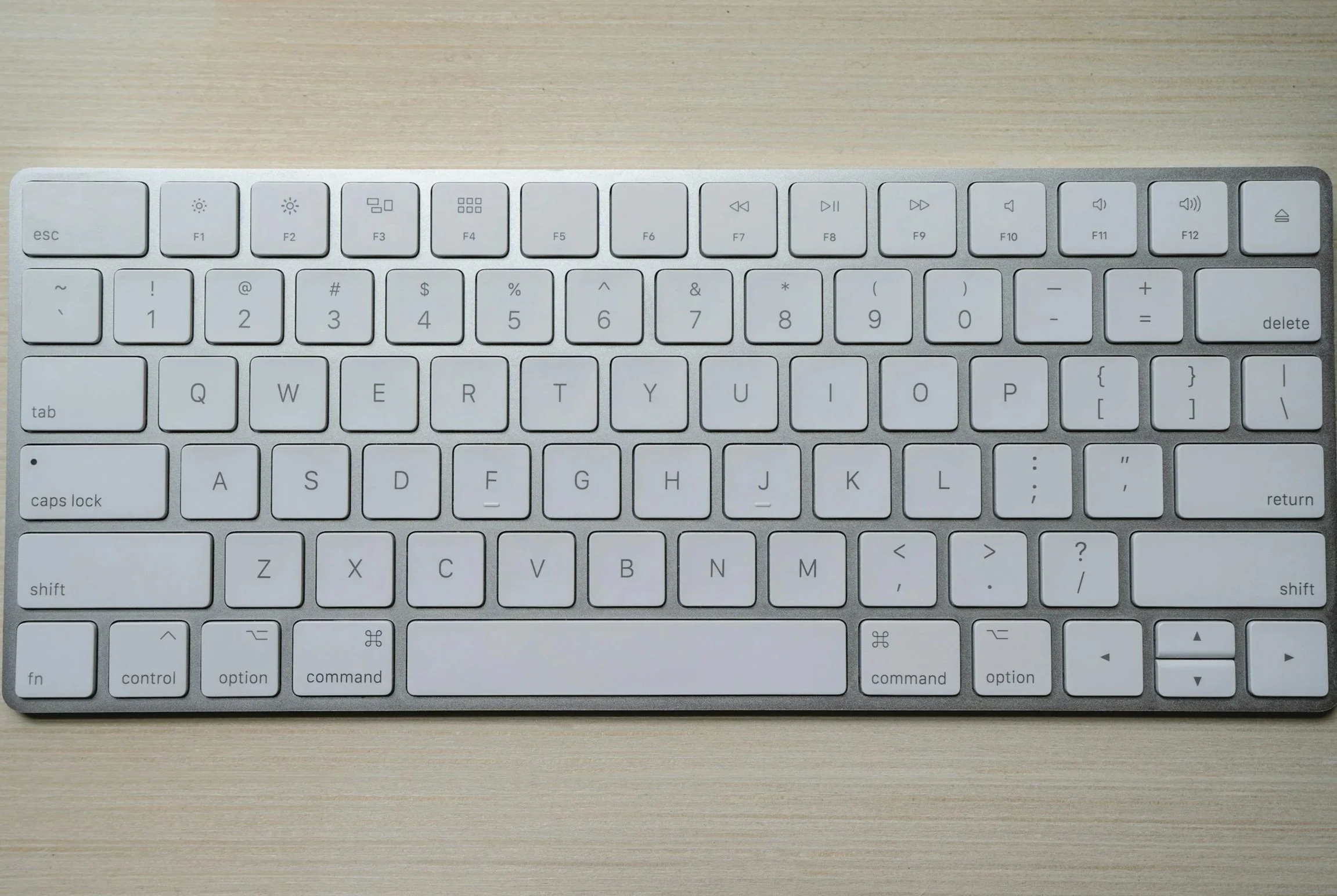 Top view of a wireless keyboard on a wooden surface with a cleverly installed "Book a Meeting" button in place of the Return key.