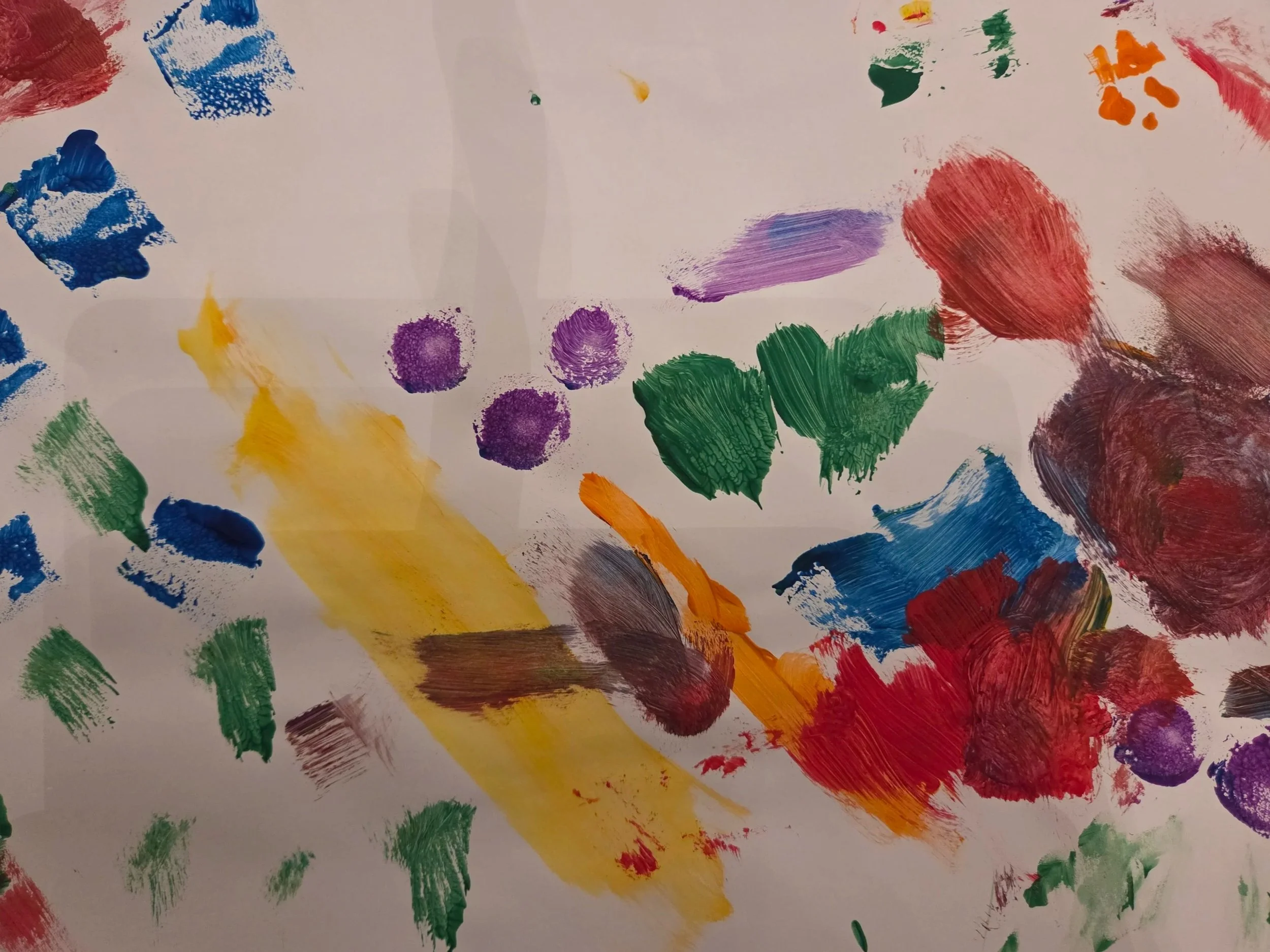A white sheet of paper with colorful abstract paint strokes and splashes in blue, red, yellow, green, purple, and orange.
