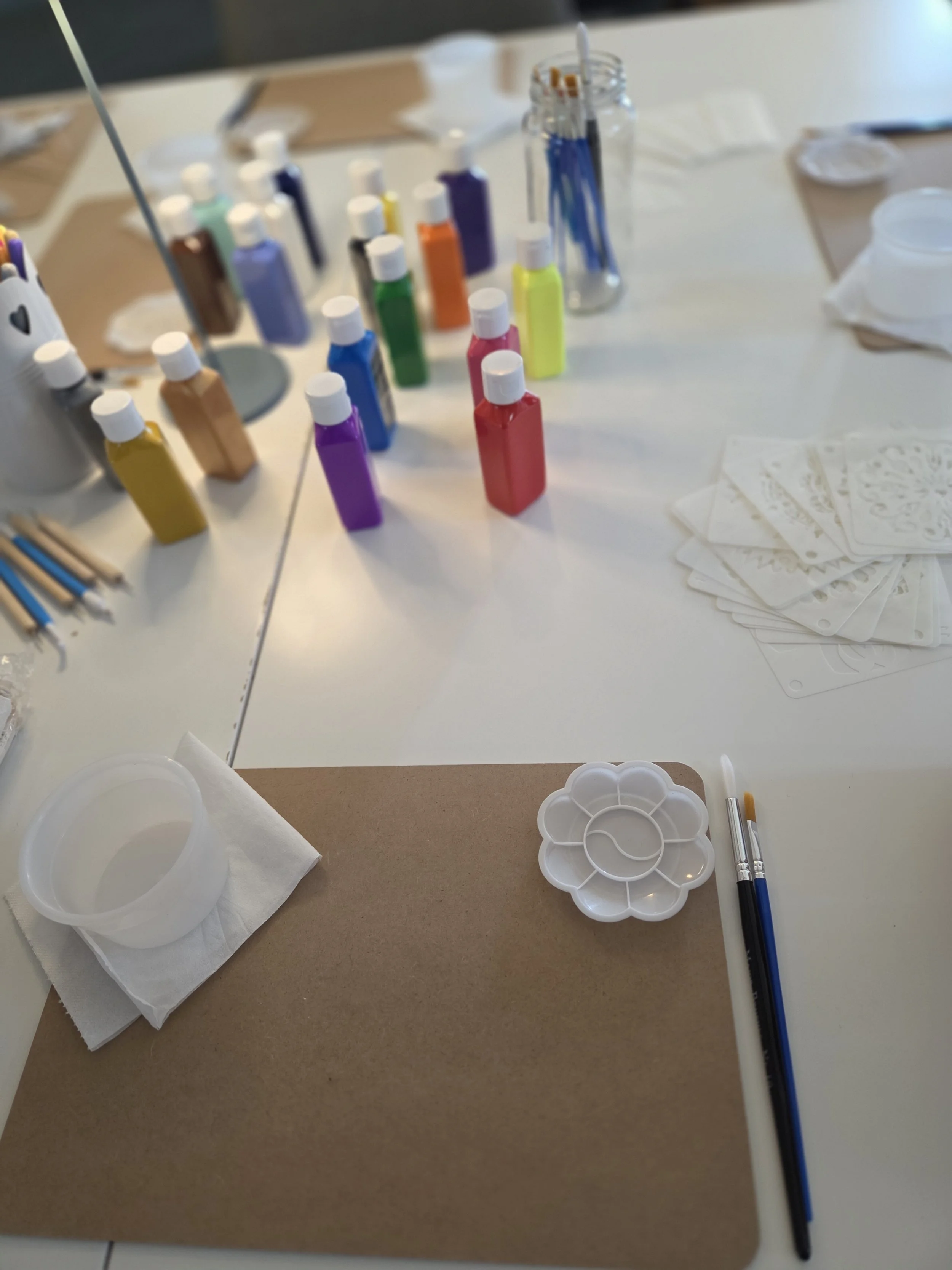 A table set up for nail art, with nail polish bottles in various colors, nail brushes, a palette, paper towels, and decorative stencils.
