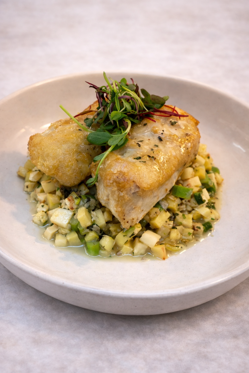 Seared white fish over a bed of seasonal vegetables tossed in a white wine emulsion 