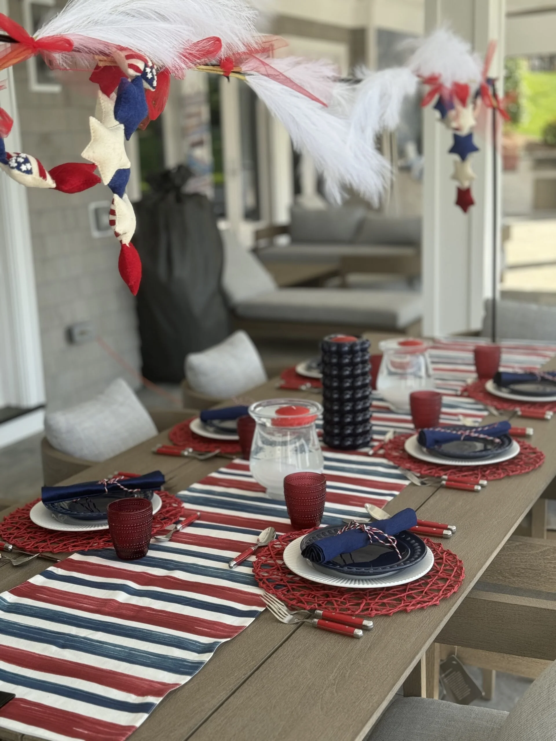 Patriotic 4th of July or Memorial Day dinner table setup with red, white, and blue tableware, star-shaped decorations, and a red, white, and blue paper table runner.
