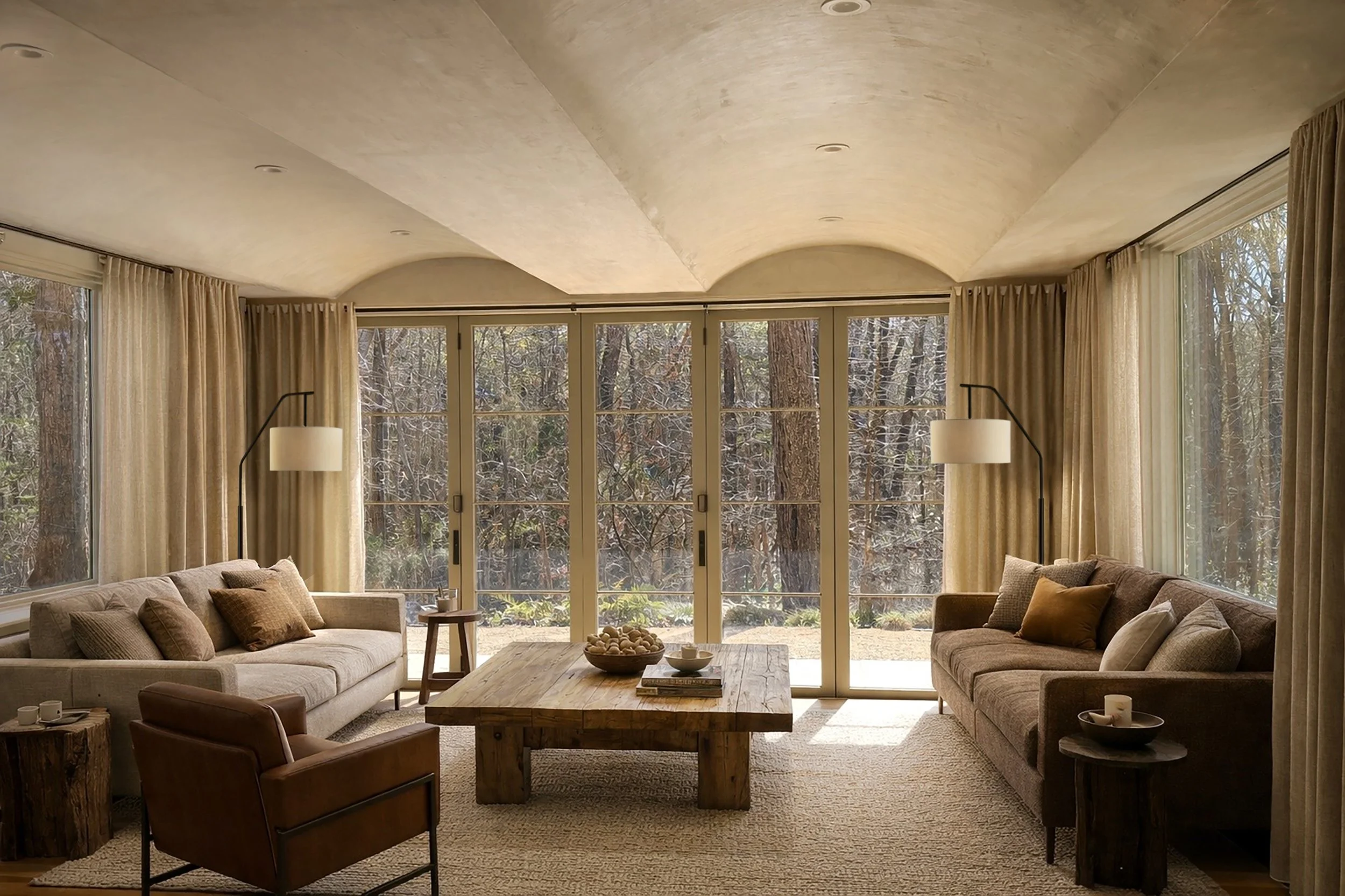 Living room with large windows, beige sofas with cushions, wooden coffee table, and a view of trees outside.