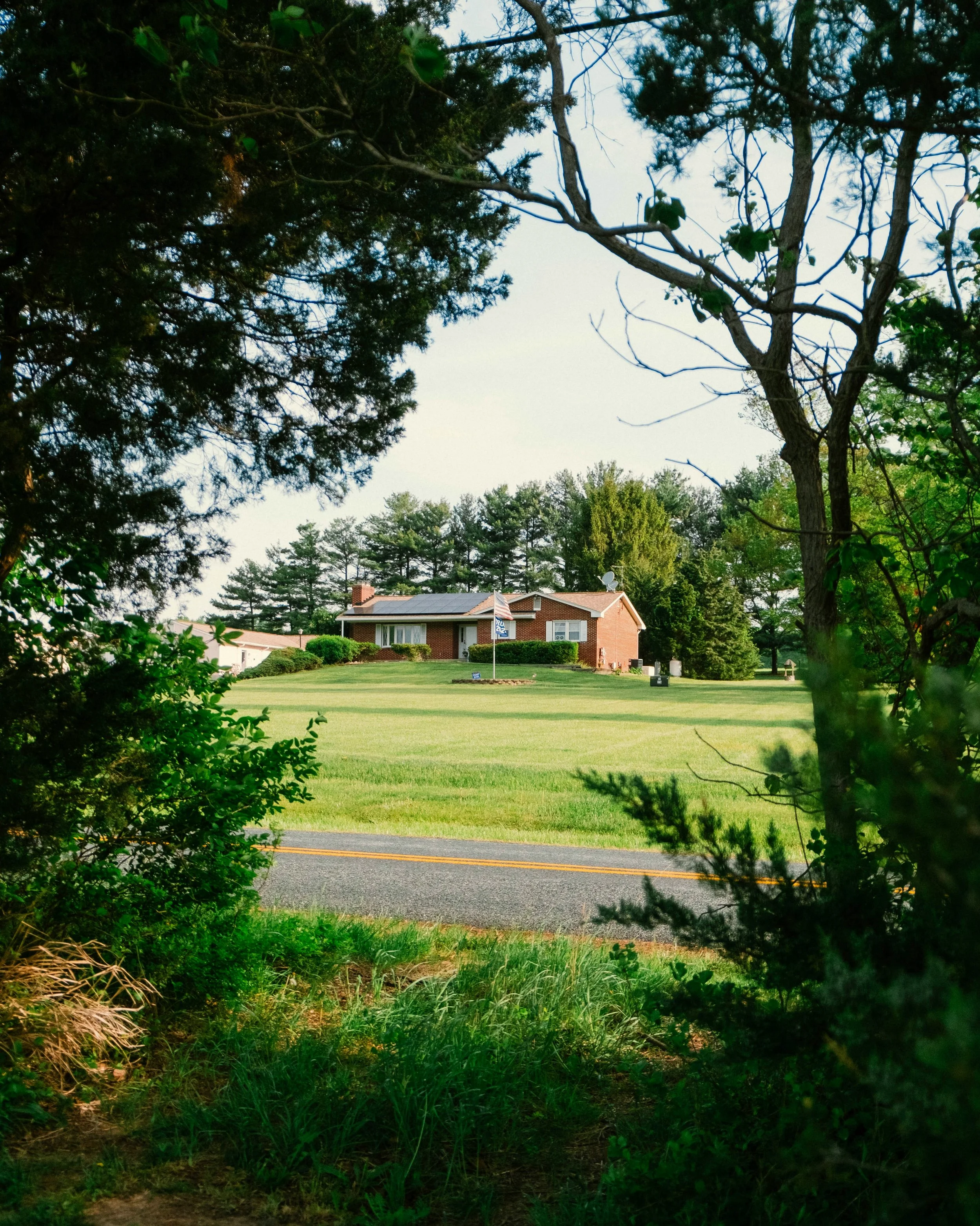 A brick house with a flagpole out front surrounded by a large lawn trimmed by BlockMow