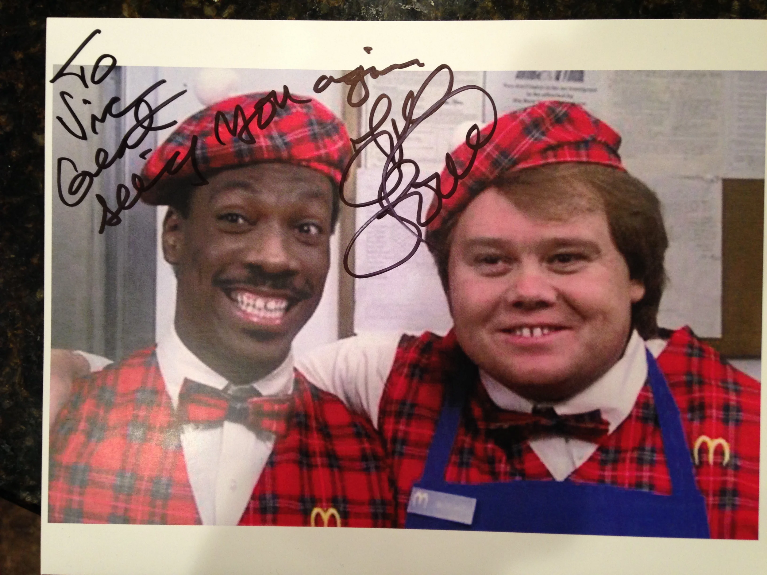 A signed photo of Louis Anderson (RIP) and Eddie Murphy from "Coming to America". The signature says, "To Vic, Great seeing you again, Love Louie".