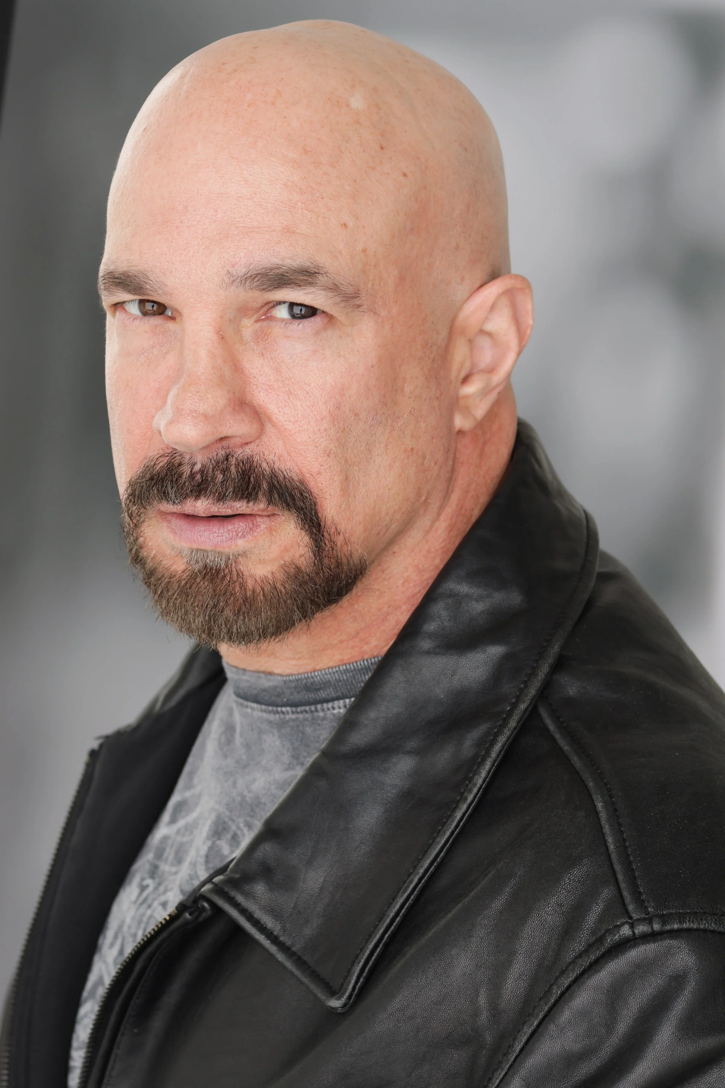 Vic Alejandro wearing a gray shirt and black leather jacket, looking at the camera.