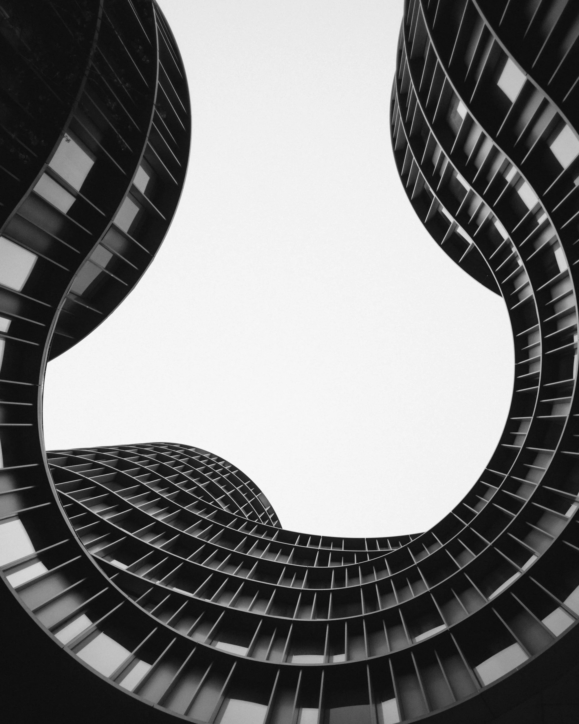 Black and white photograph of the spiraling interior of a modern building, taken from the ground looking up.