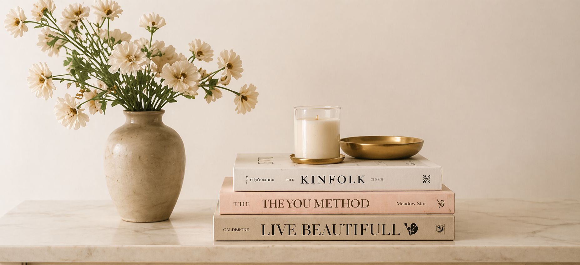 Neutral luxury flat lay with flowers, candle, and stacked books featuring The YOU Method by Meadow Star, founder of Wild Beauty Society.