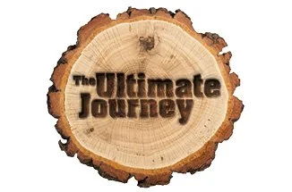 A wooden log slice with the text 'The Ultimate Journey' burned into the surface.