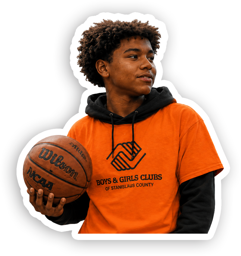 Young person with curly hair holding a basketball, wearing an orange T-shirt with 'Boys & Girls Clubs of Stanislaus County' logo, standing against a black background.