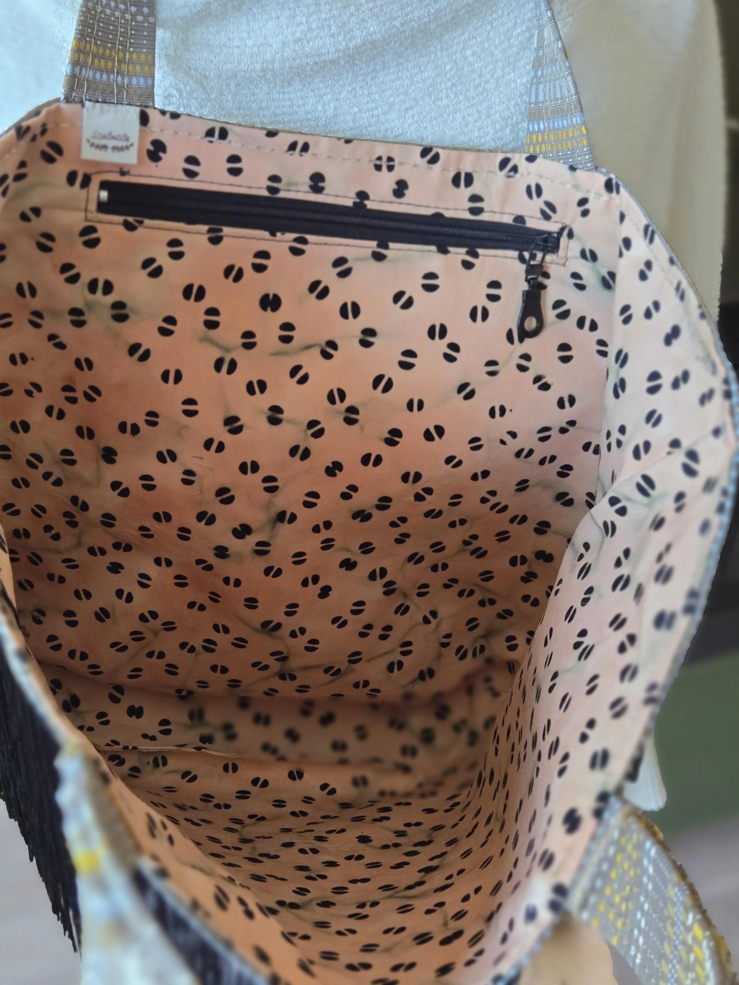 Inside of a fabric bag with black polka dots and a black zippered pocket. Fun complimentary interiors to dbfourdesign totes