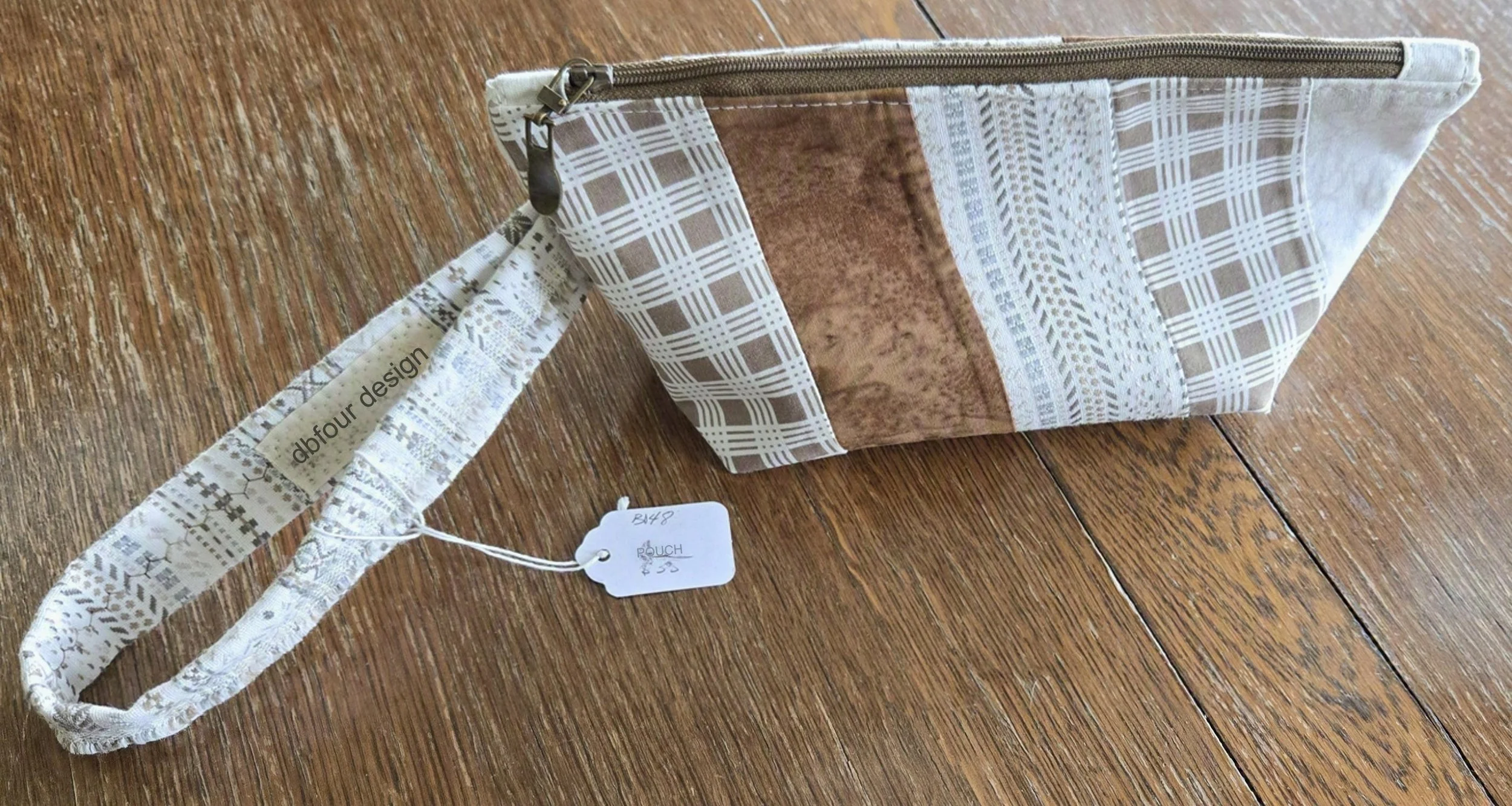 A fabric pouch with a plaid and floral pattern with attached wrist strap