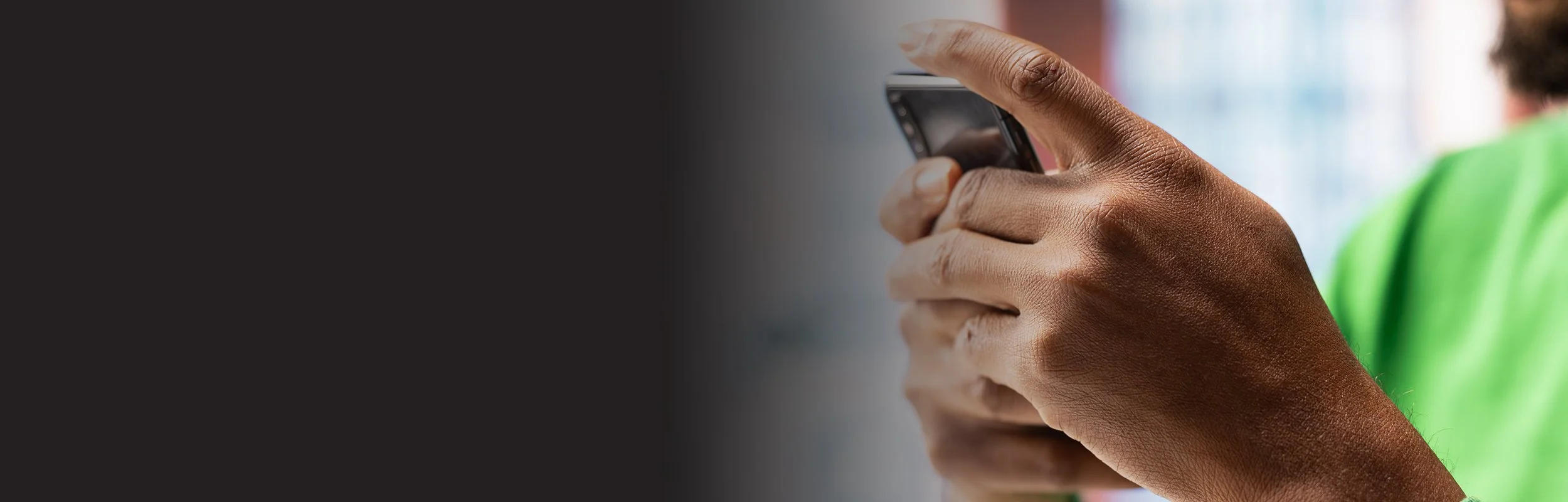 Person with dark skin holding a smartphone, focusing on their hands and the device.