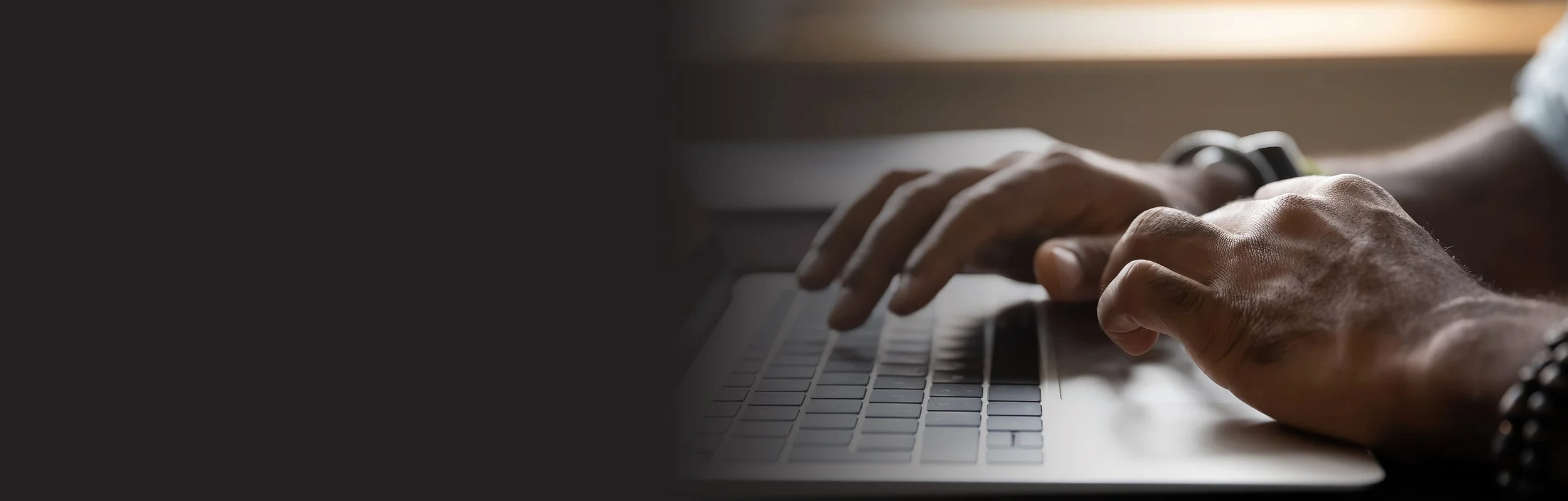 Close-up of hands typing on a laptop keyboard.