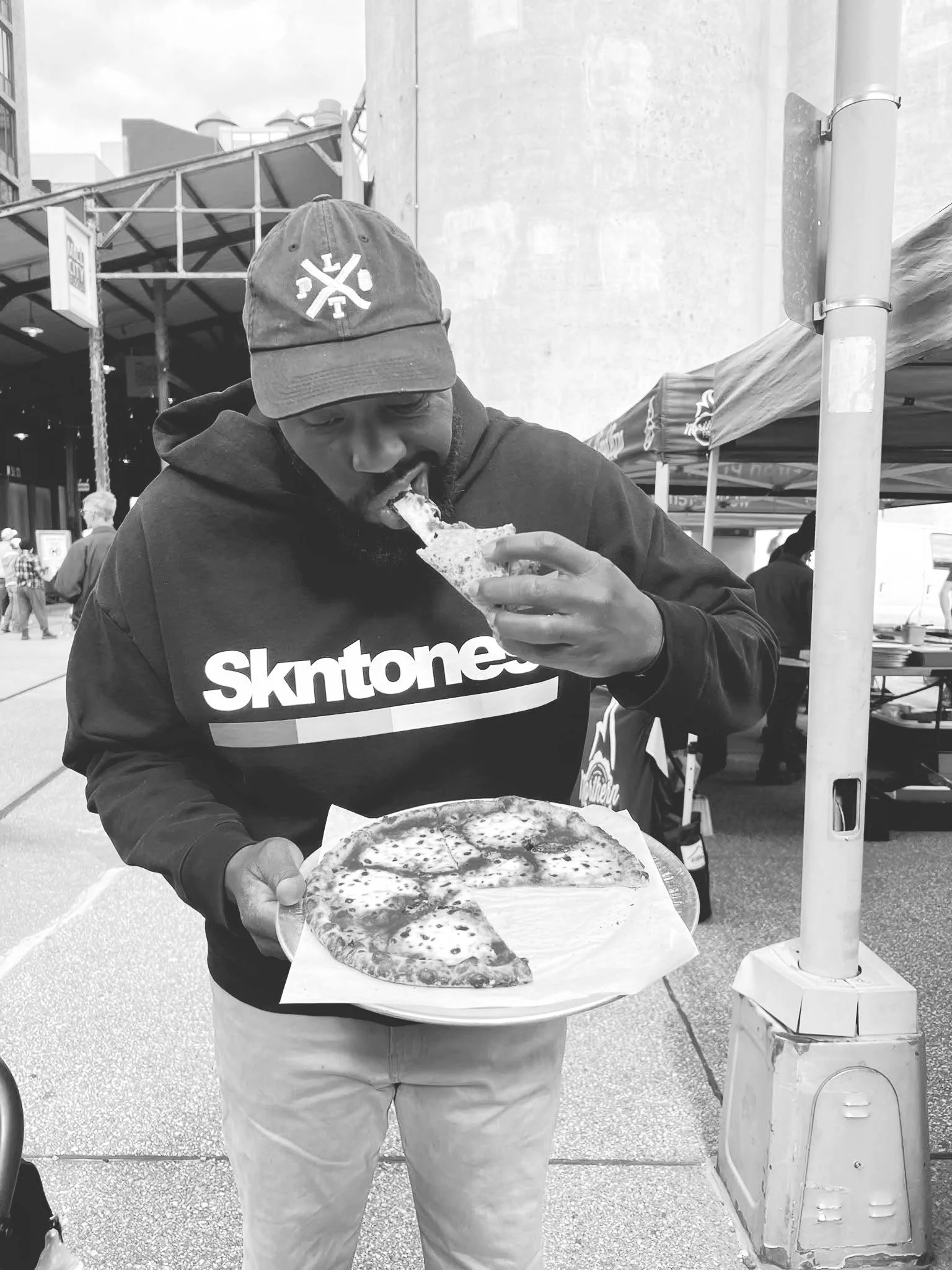 A man wearing a baseball cap and a hoodie with 