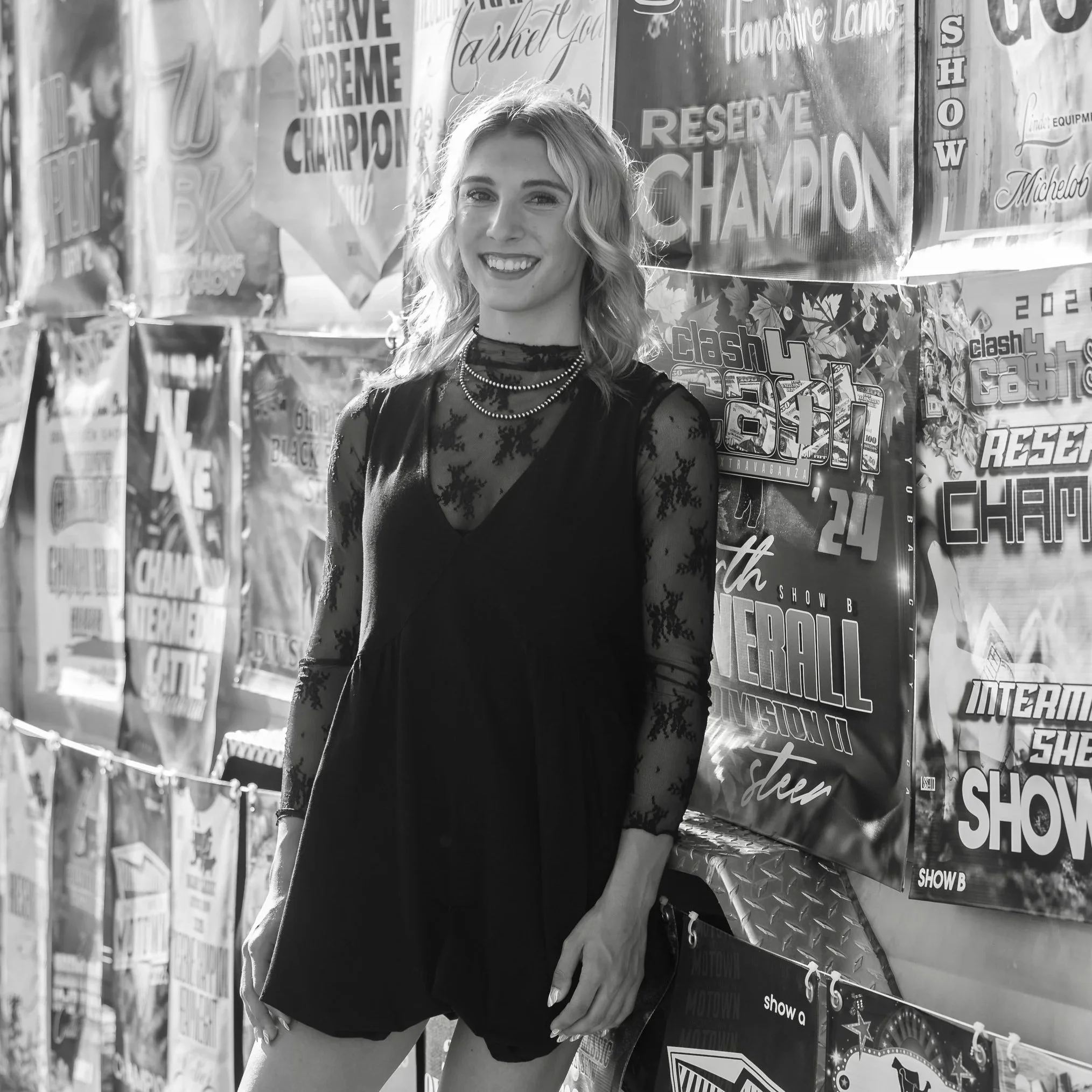 A smiling woman with wavy hair standing in front of a display of posters and signs.