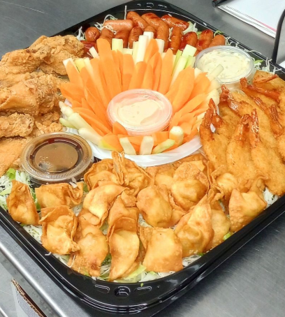 Fried chicken, fried wontons, vegetables with ranch dip, and various dipping sauces on a black tray.