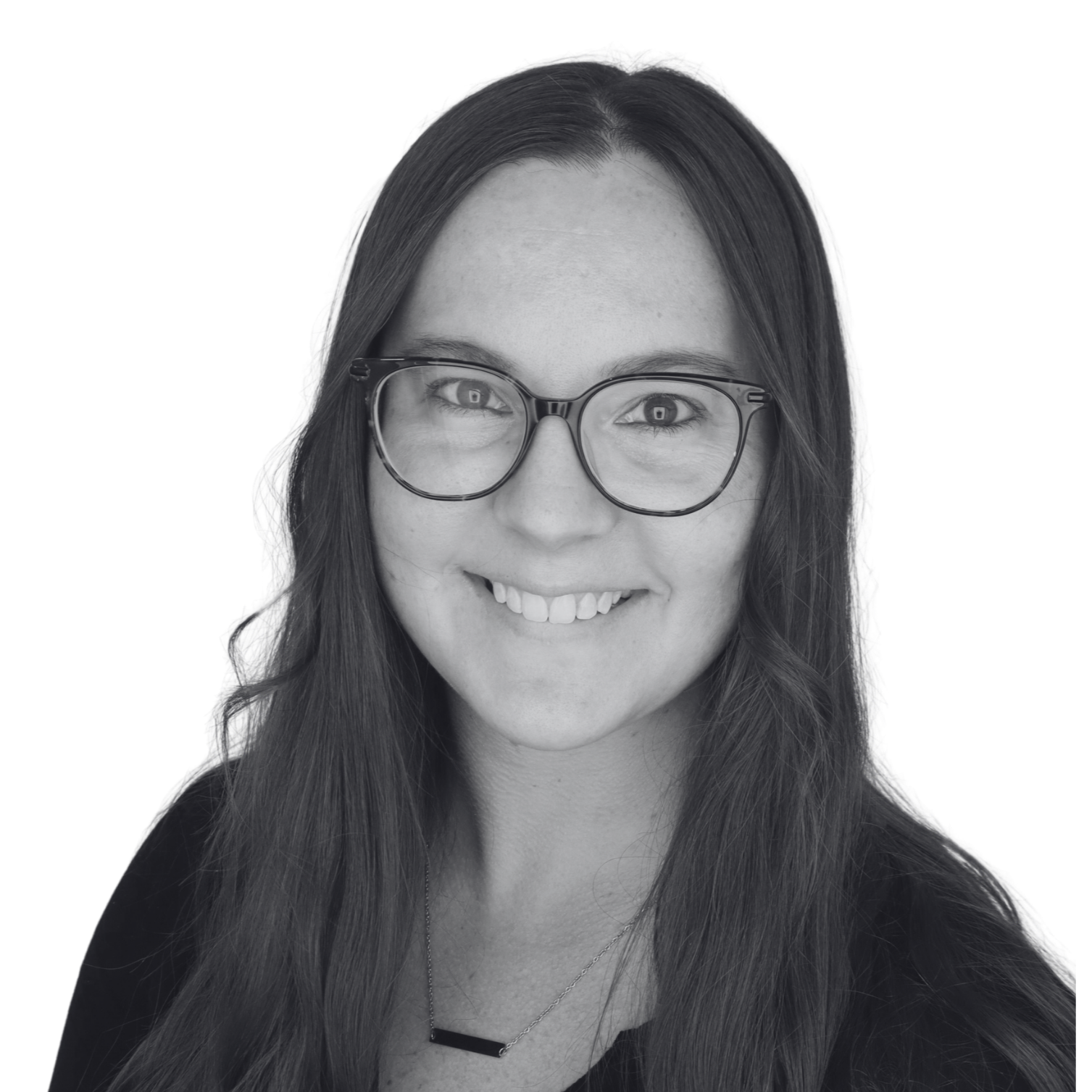 A smiling young woman with long hair, wearing glasses and a necklace, black top, and a slight smile.