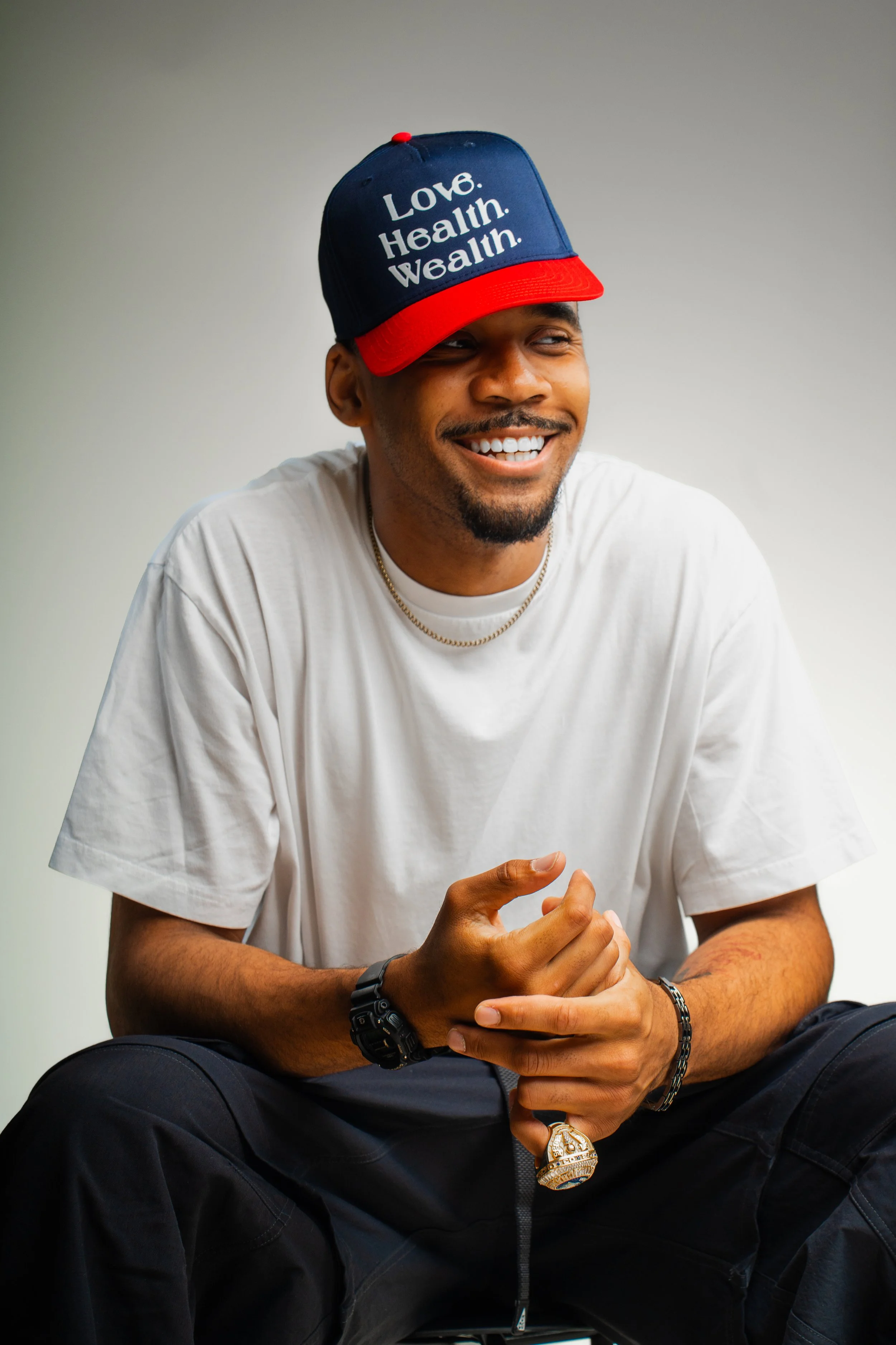 Model wearing navy and red Love Health Wealth hat, BOI unisex streetwear