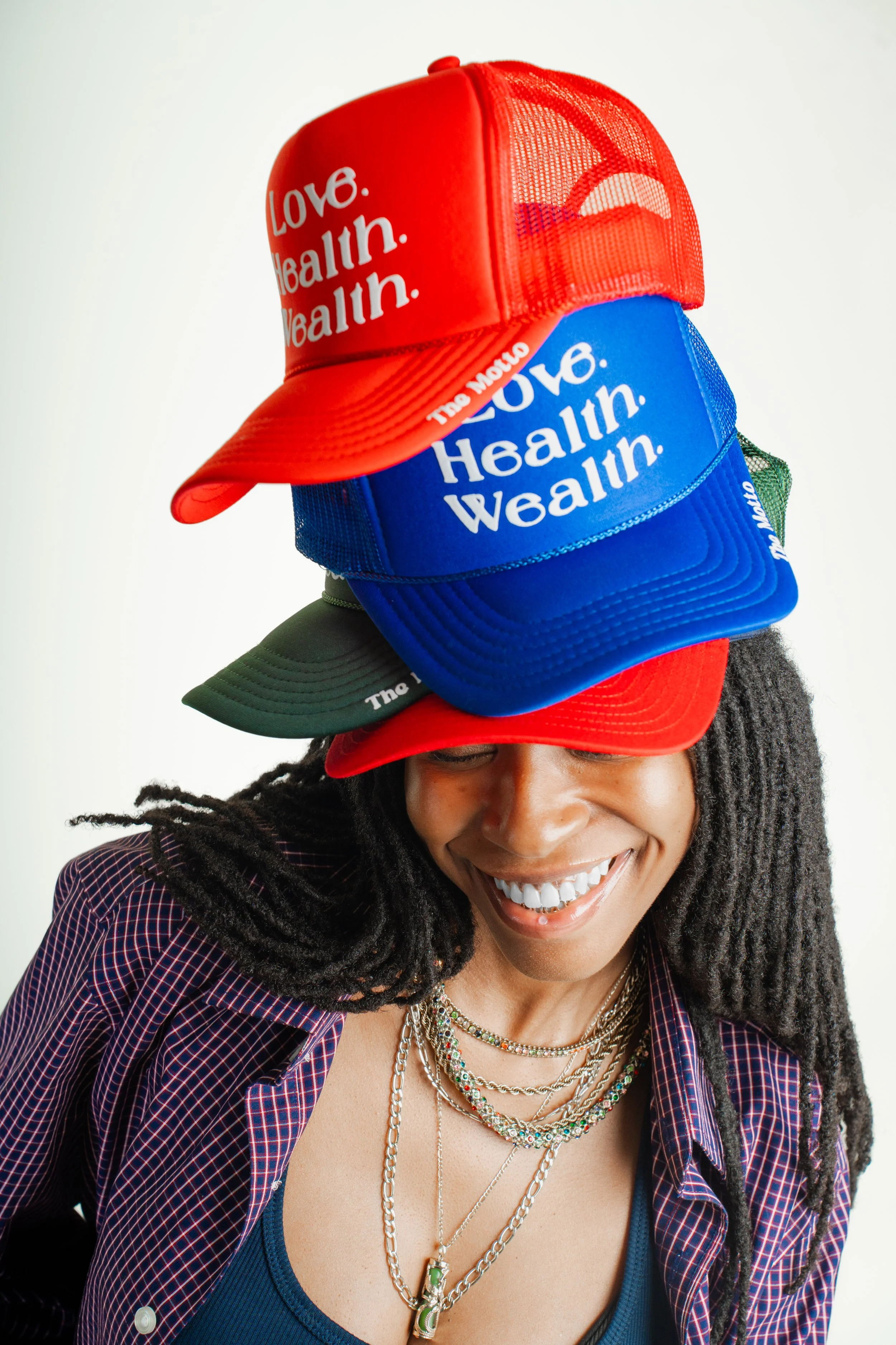 Model wearing multiple BOI Collection hats stacked, showcasing unisex streetwear style 