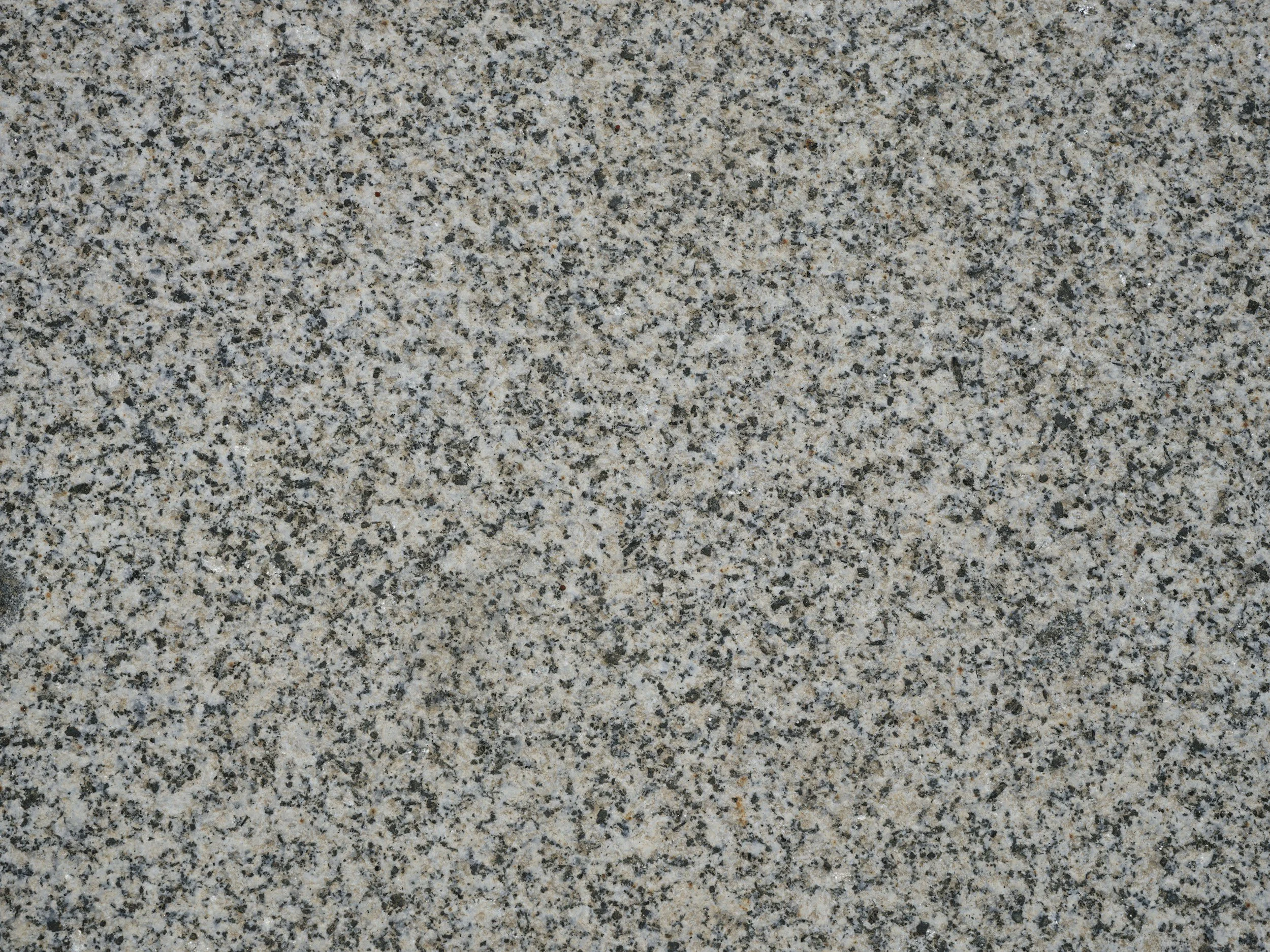 Close-up of a speckled granite countertop, showing a mixture of black, gray, white, and tan mineral grains.