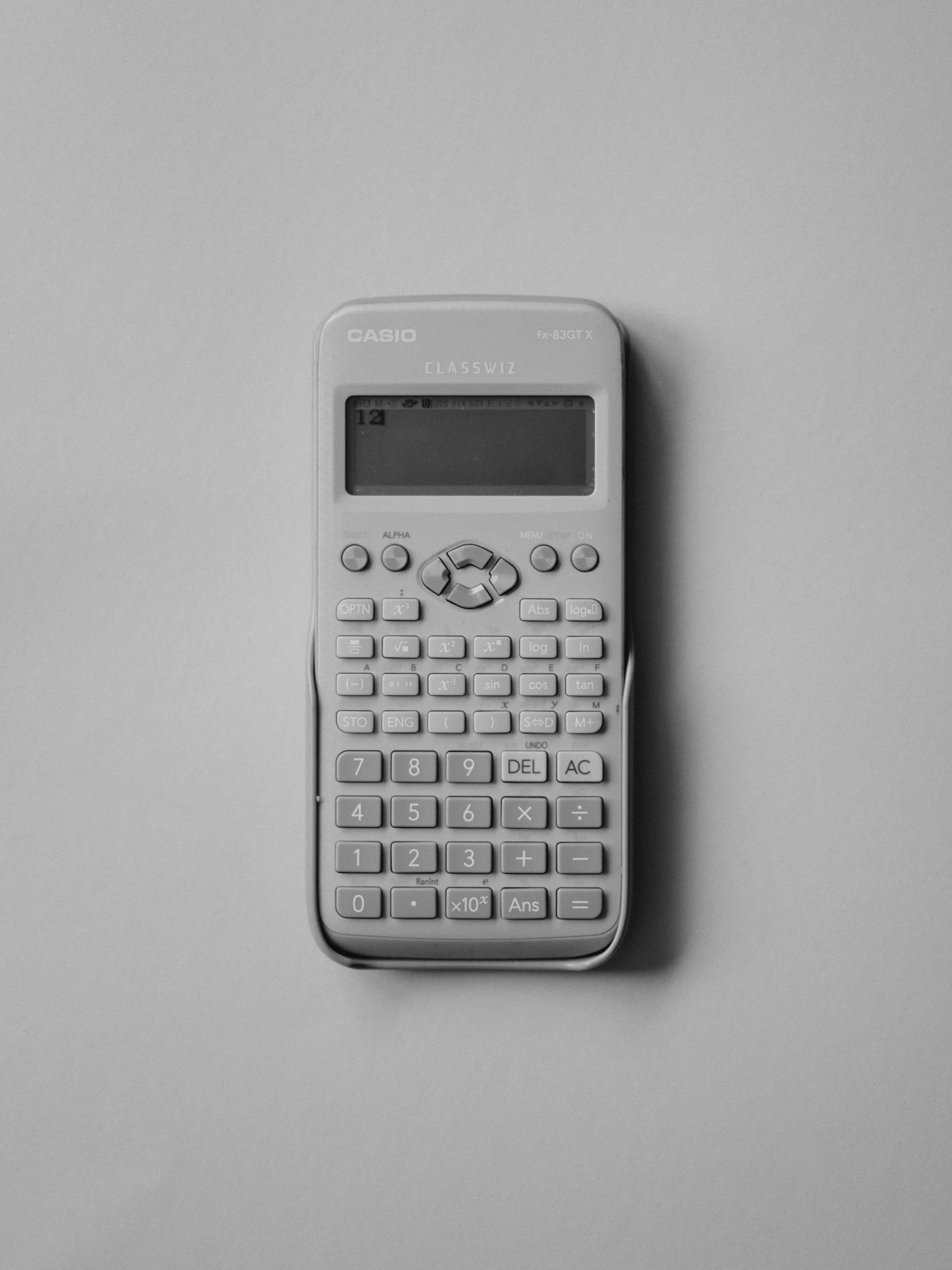 A grayscale image of a calculator on a plain surface.