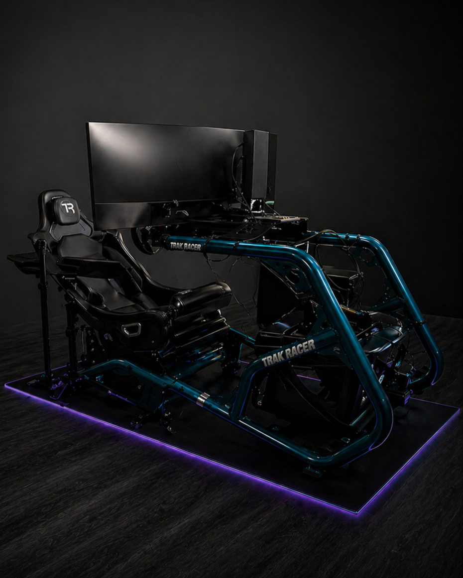 A racing simulator setup including a racing seat, a large monitor, and a motion platform with blue metal bars labeled 'TRAK RAGER,' all on a floor with purple LED lighting.